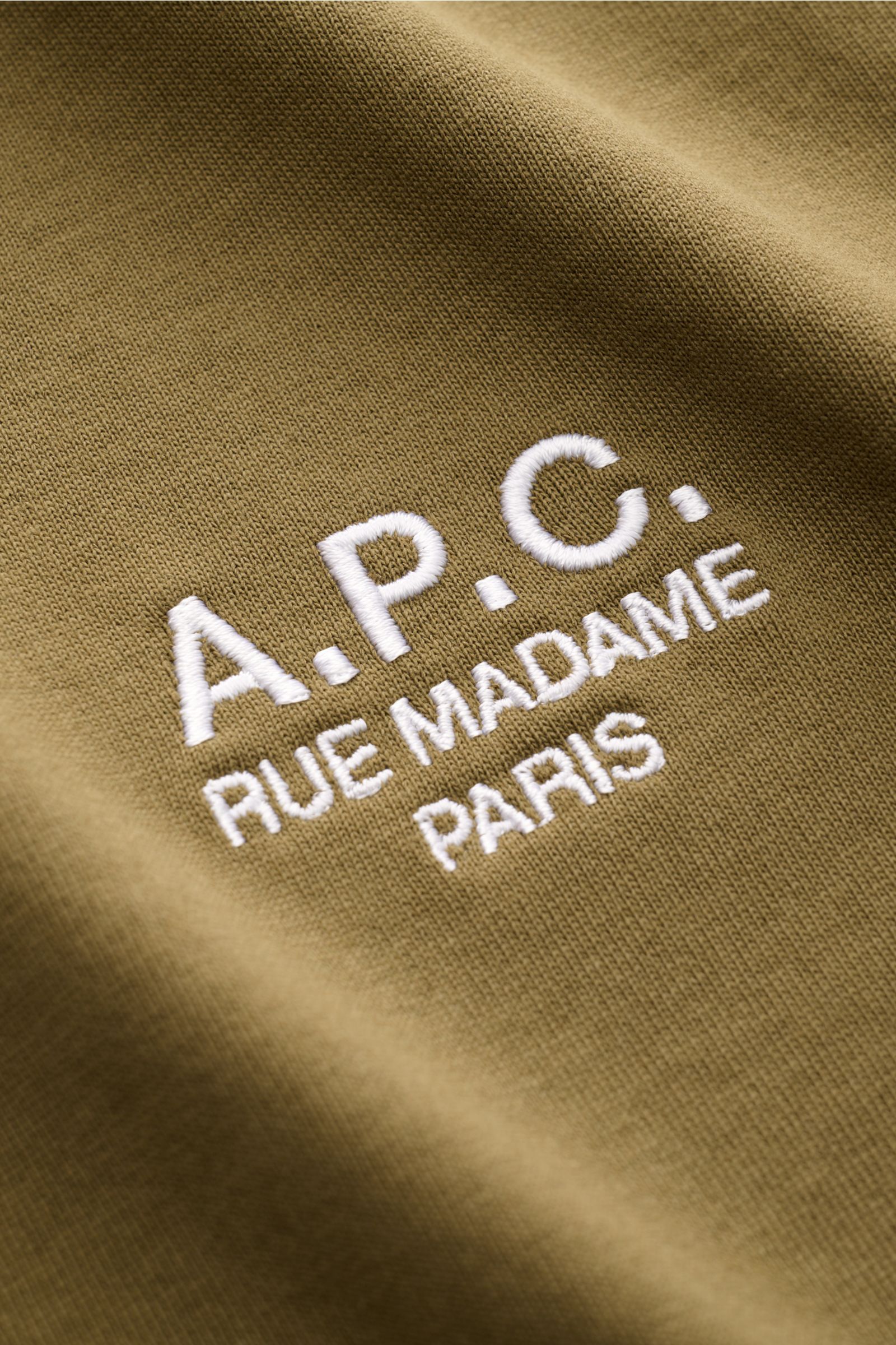 Close-up front view of the olive A.P.C. Rundhals-T-Shirt 'Standard Rue Madame' showing white embroidered logo on soft cotton jersey fabric. 

Clean, cool, A.P.C. – das T-Shirt 'Standard Rue Madame' bringt französisches Understatement auf den Punkt. Aus