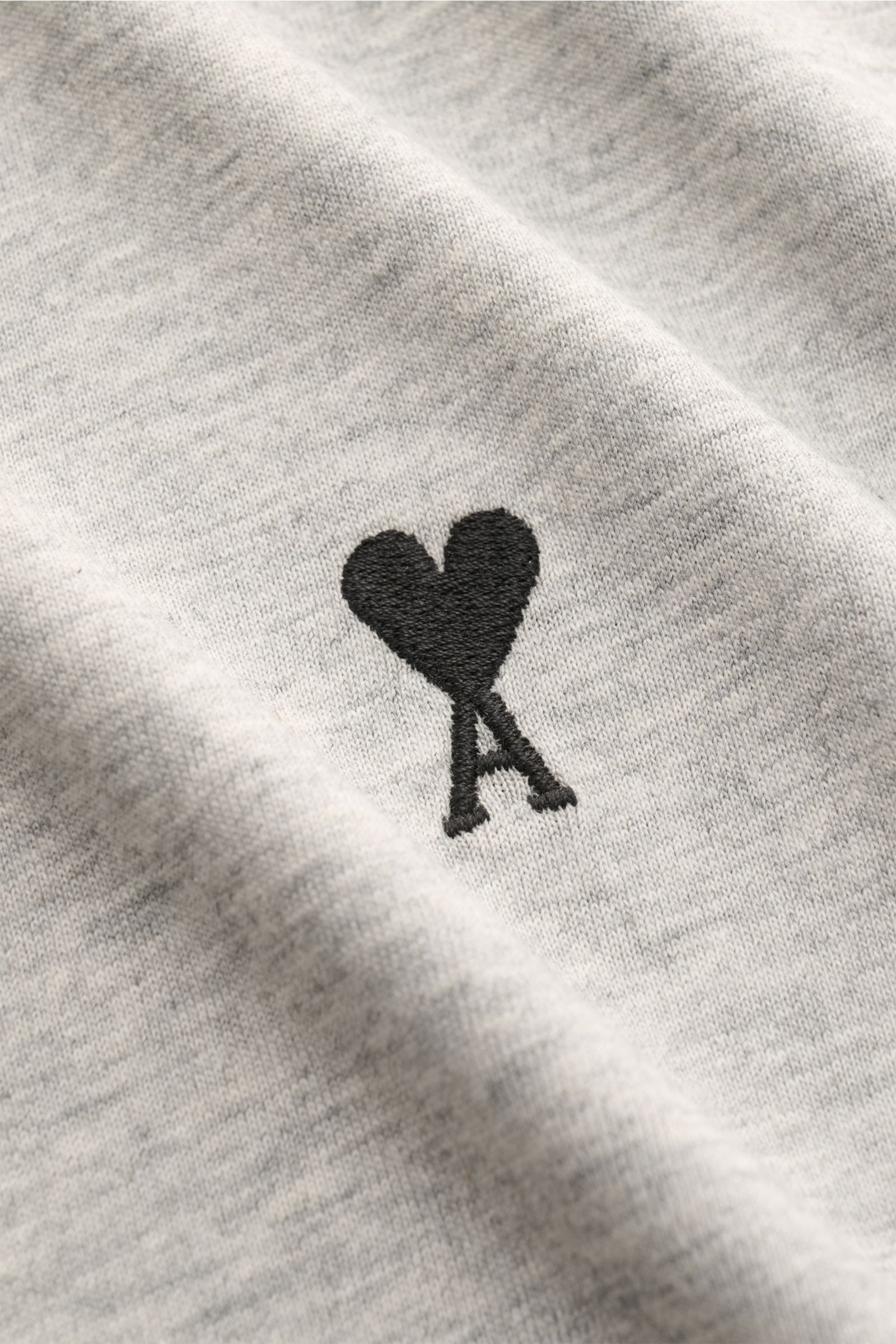 Nahaufnahme des Ami Paris Rundhals-T-Shirt hellgrau aus reiner Baumwolle mit schwarzem Herz-Stitching auf der Brust, weicher Jersey-Stoff.