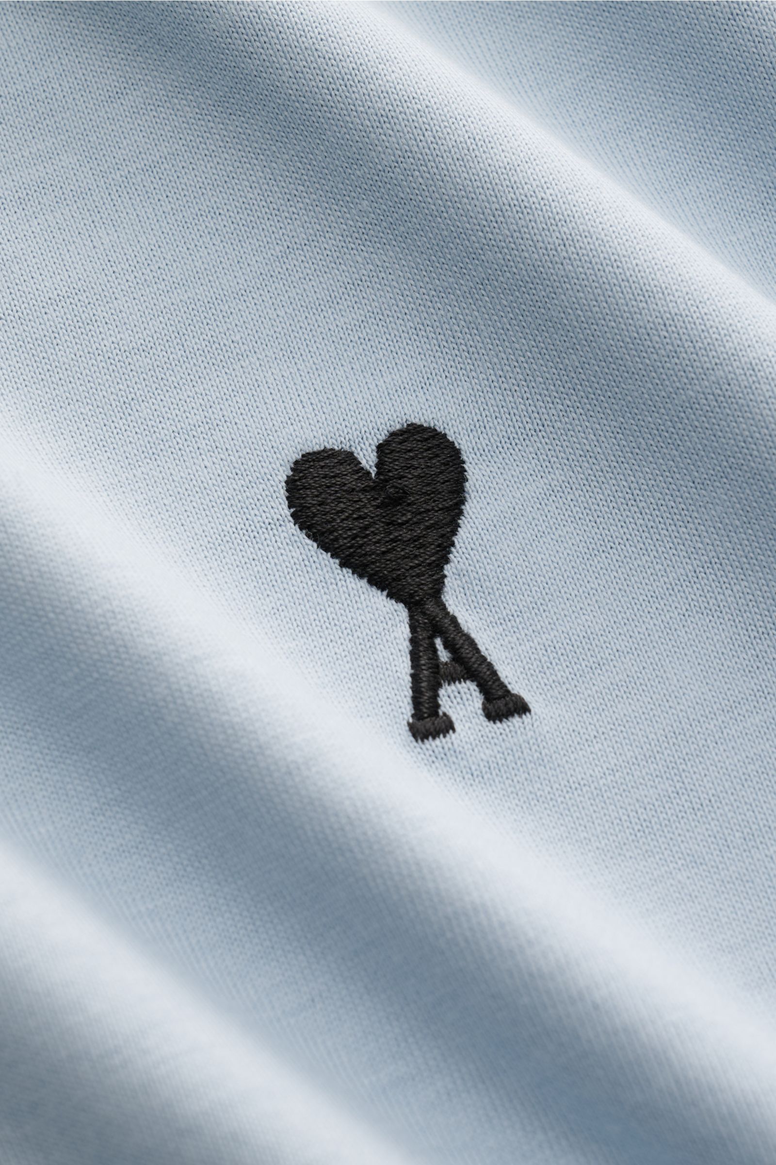 Close-up front view of Ami Paris Rundhals-T-Shirt rauchblau showing soft pure cotton jersey fabric and black heart-stitching on the chest. Klassisches Jersey-Basic vom französischen Label AMI PARIS: Dieses T-Shirt mit Rundhalsausschnitt ist aus reiner 