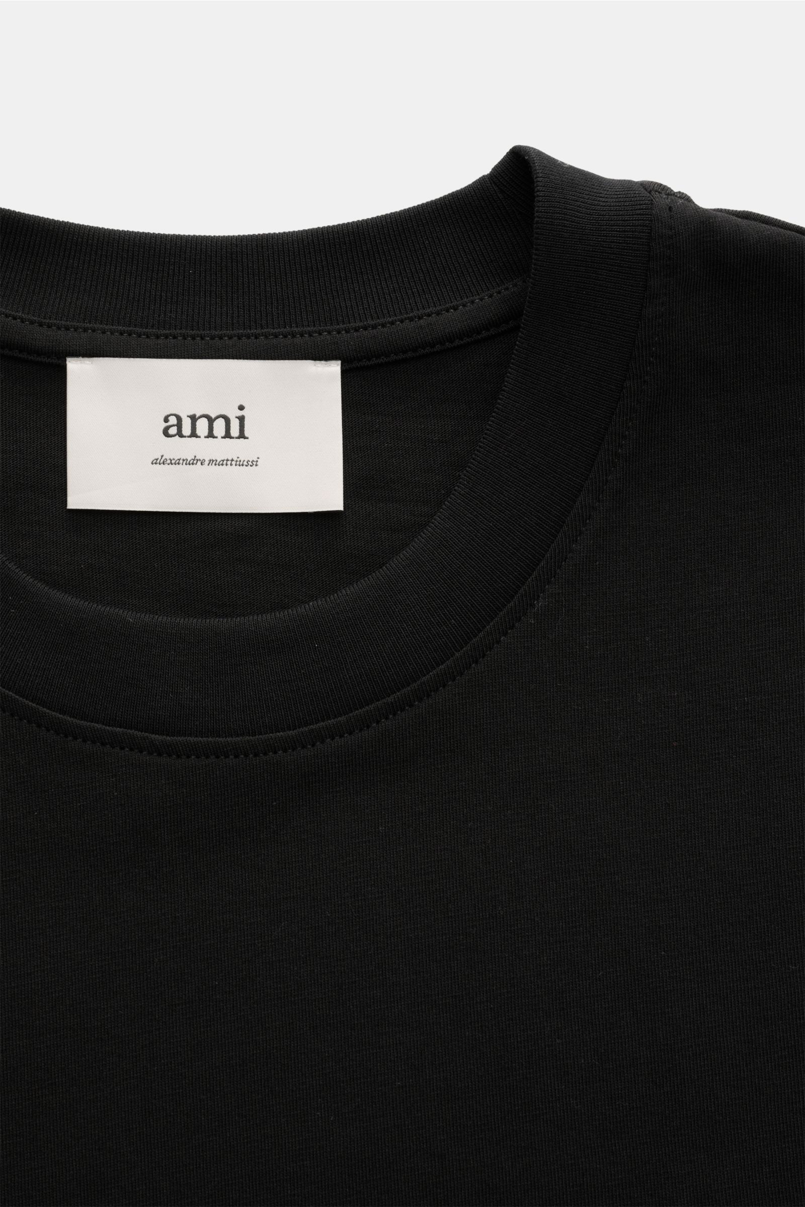 Close-up front view of the Ami Paris Rundhals-T-Shirt schwarz showing the black round neckline and interior label.

Klassisches Jersey-Basic vom französischen Label AMI PARIS: Dieses T-Shirt mit Rundhalsausschnitt ist aus reiner Baumwolle gearbeitet un