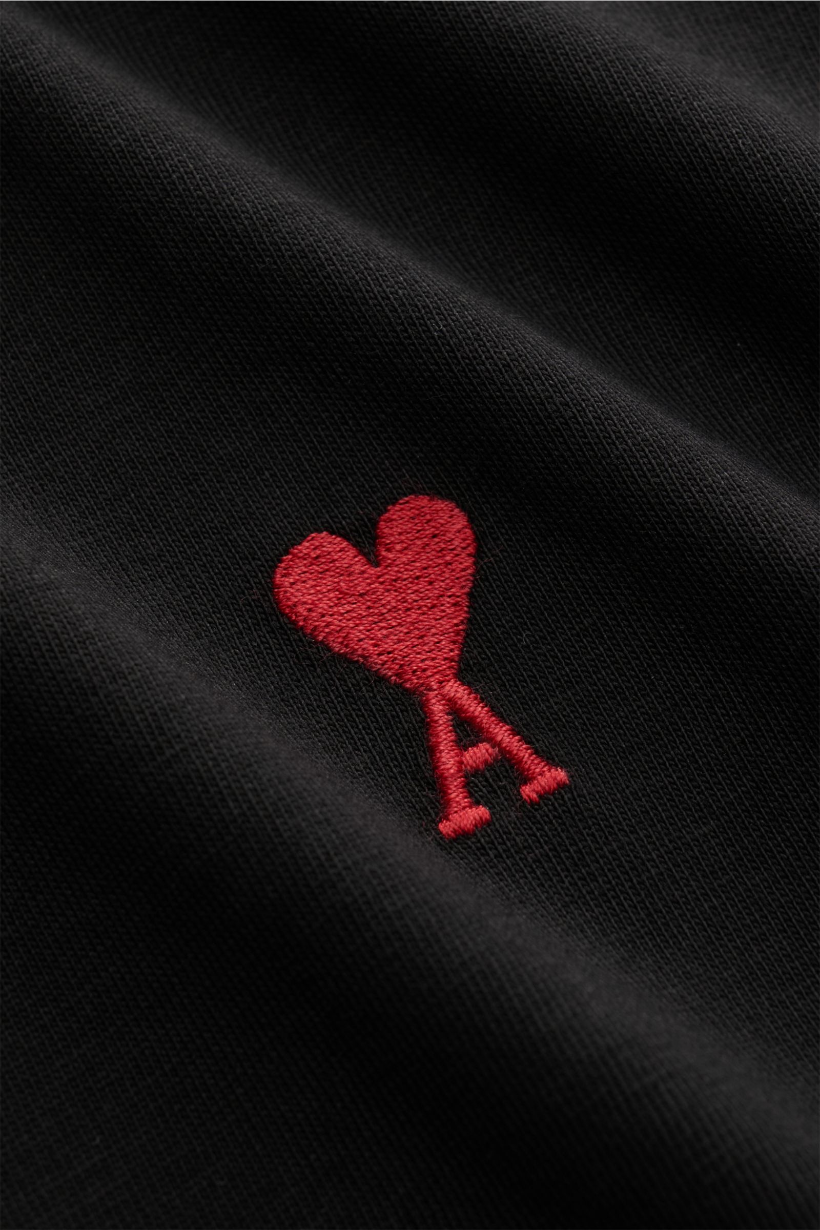 Close-up front view of the Ami Paris Rundhals-T-Shirt schwarz showing the red heart stitching on soft black pure cotton jersey fabric. 

Klassisches Jersey-Basic vom französischen Label AMI PARIS: Dieses T-Shirt mit Rundhalsausschnitt ist aus reiner Ba
