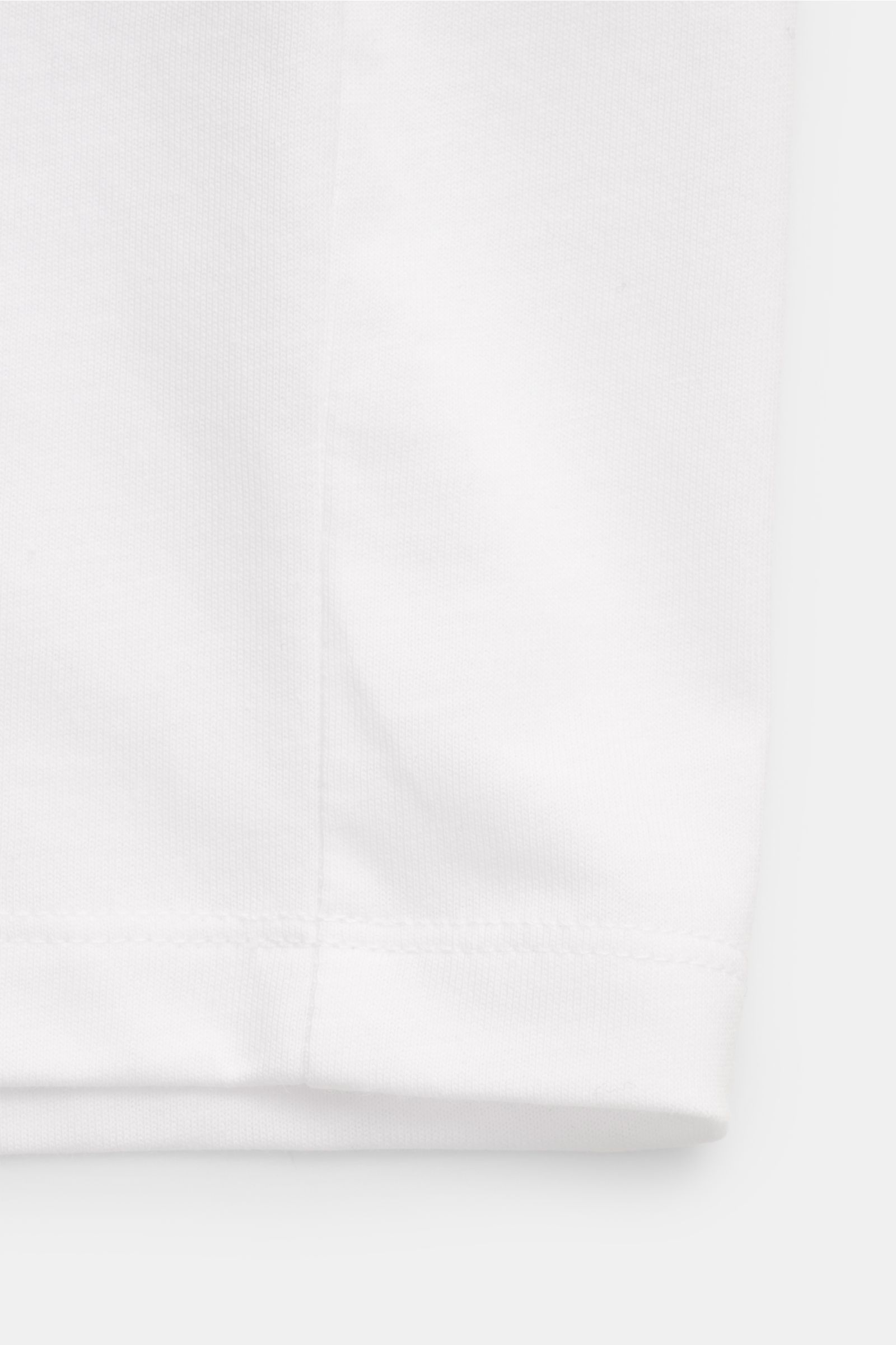 Close-up of the bottom hem of the Ami Paris Rundhals-T-Shirt weiß, showing white pure cotton jersey fabric with fine stitching, photographed from the front side.

Description: Klassisches Jersey-Basic vom französischen Label AMI PARIS: Dieses T-Shirt m