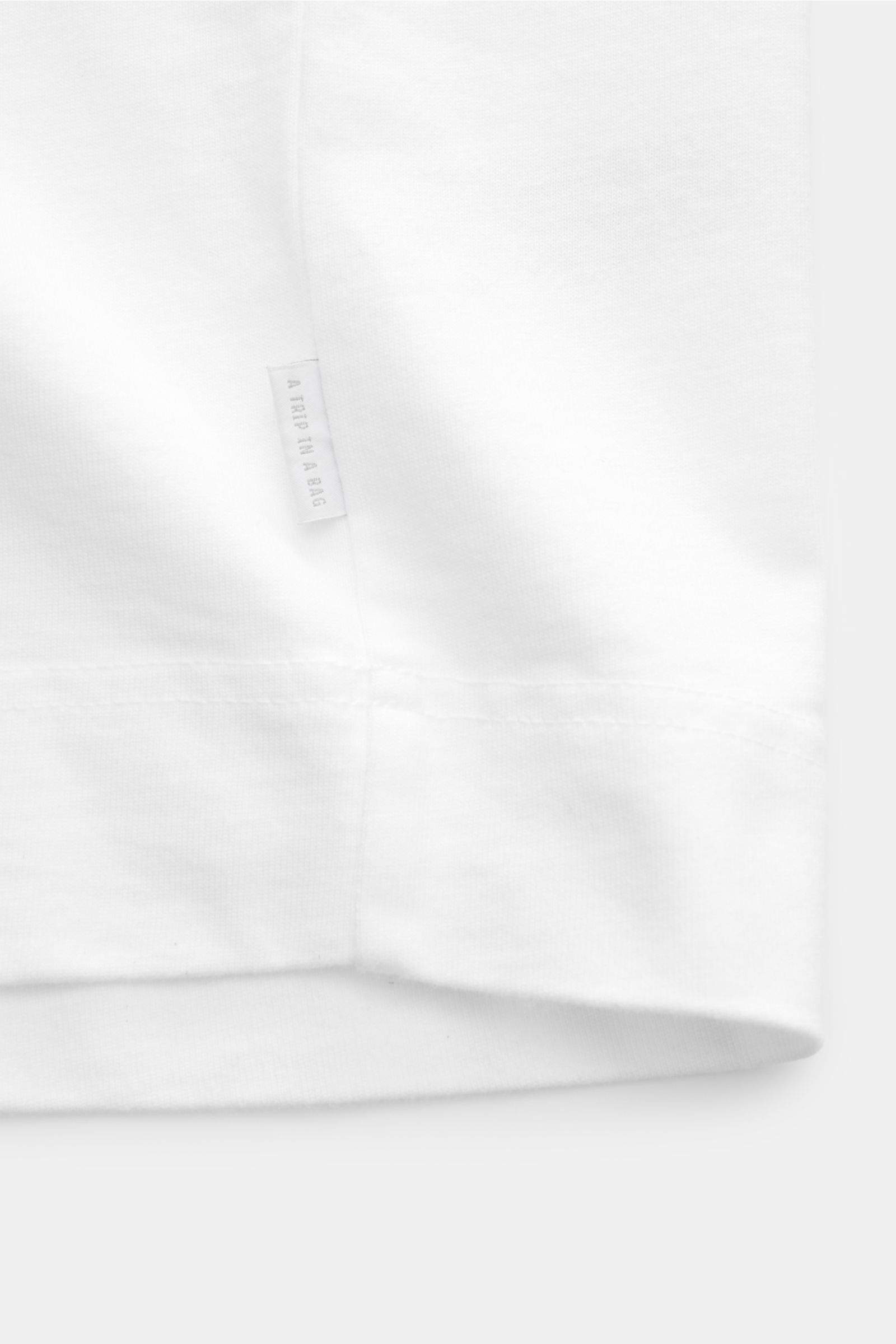 Detailaufnahme des weißen 04651/ A trip in a bag Rundhals-T-Shirt 'Nunu Tee' mit Weblabel an der Seitennaht, Jersey aus Baumwolle.