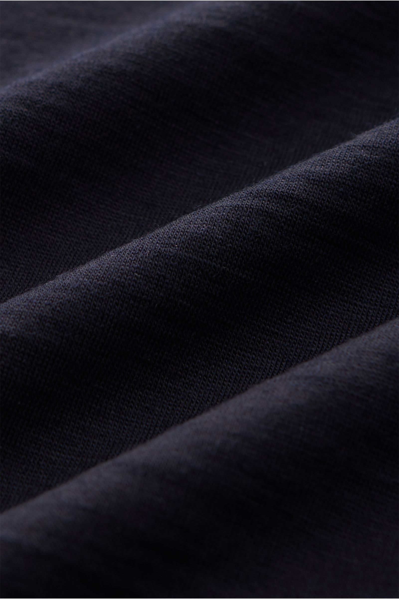 Close-up fabric texture of The Product is the Hero Merino T-Shirt 'Wool Tee' navy, showing soft, fine merino wool knit.

THE PRODUCT IS THE HERO verleihen dem klassischen T-Shirt-Schnitt bei ihrem 'Wool Tee' mit einem Jersey aus reiner Merinowolle ein 