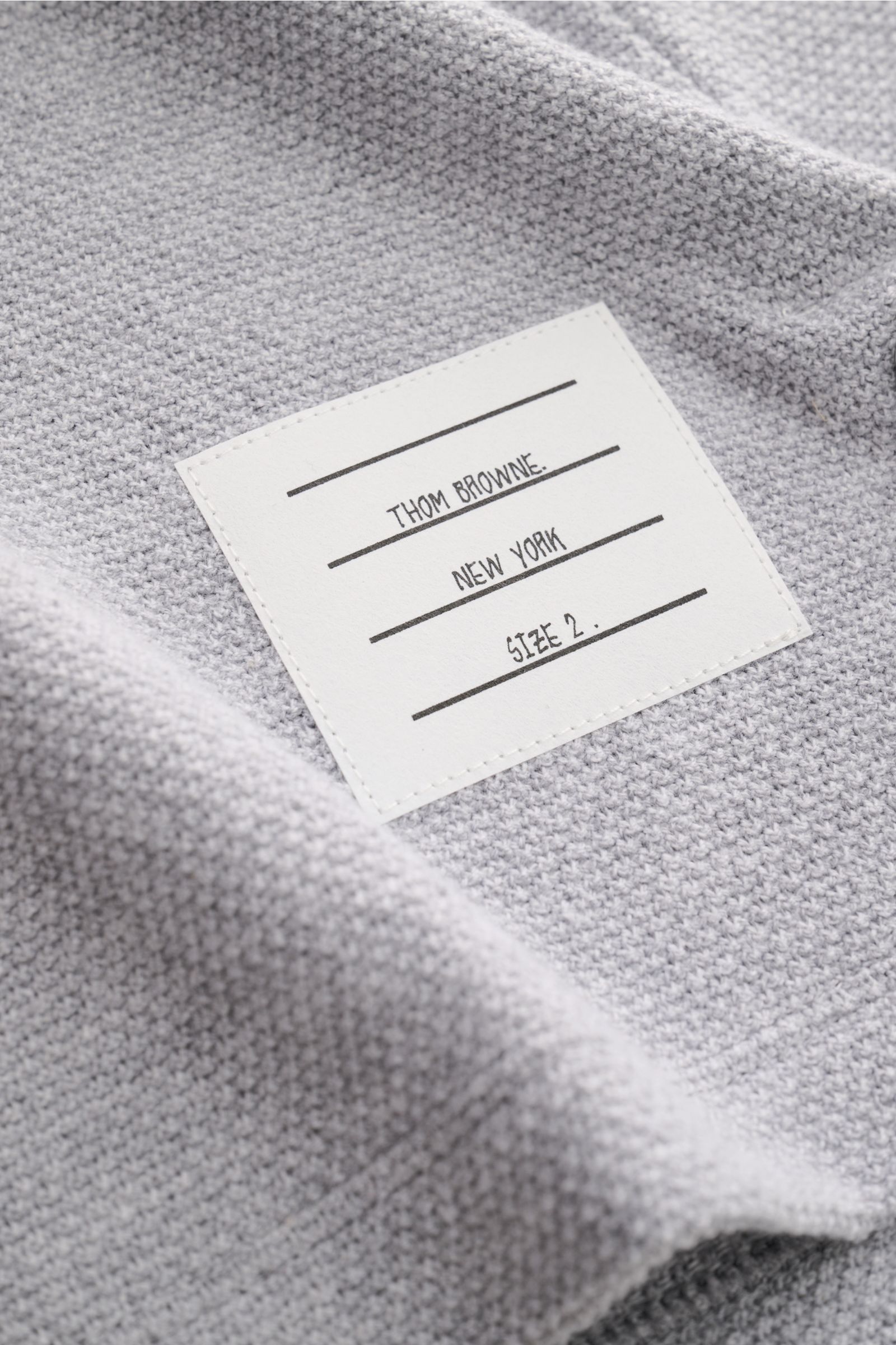 Nahaufnahme des graumelierten Thom Browne Rundhals-T-Shirts, Detail des Etiketts auf strukturierter, luftiger Baumwolle mit Regular Fit.