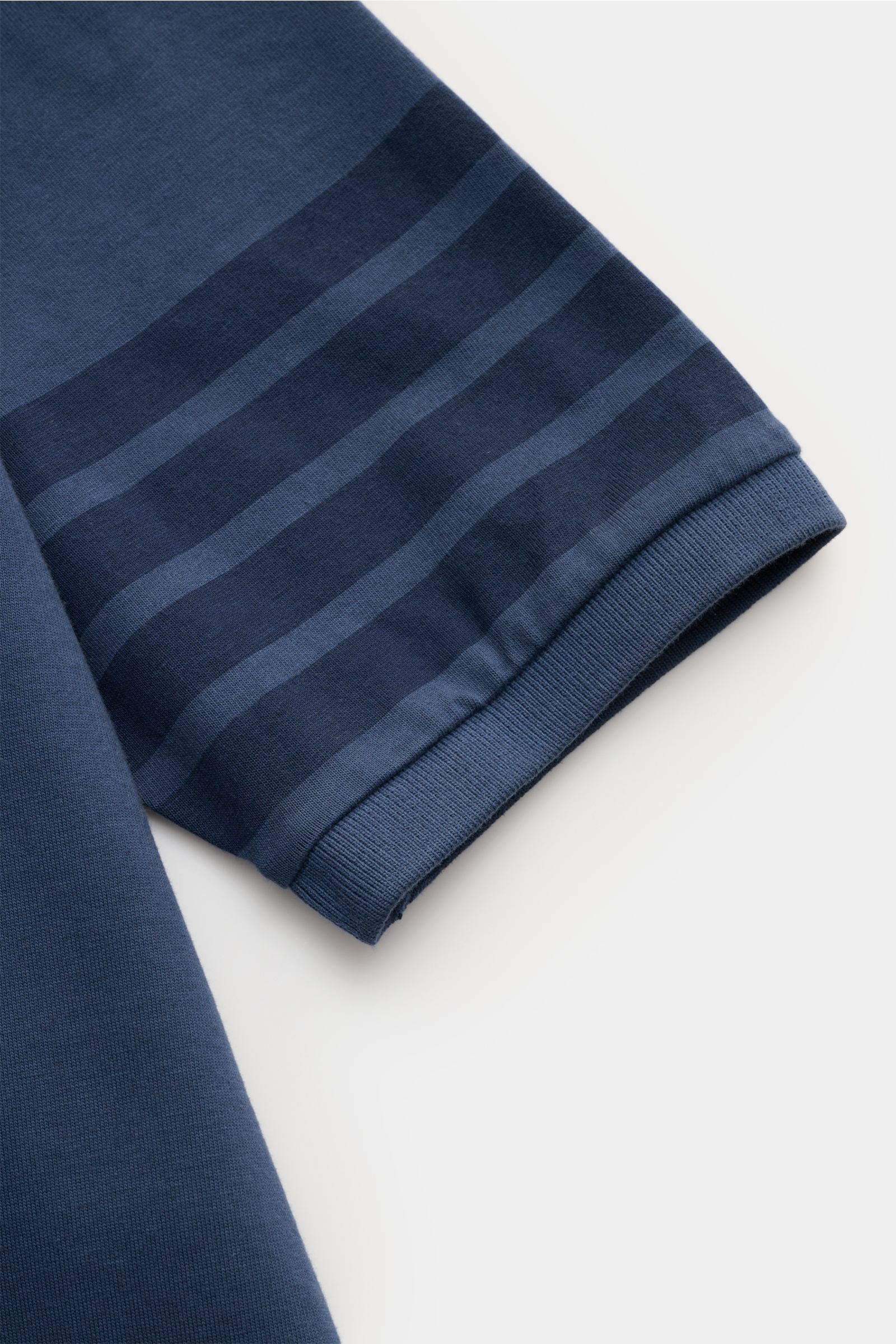 Nahaufnahme des Ärmels vom graublauen Thom Browne Rundhals-T-Shirt mit markentypischen Streifen, breitem Saumbündchen aus schwerer, reiner Baumwolle.