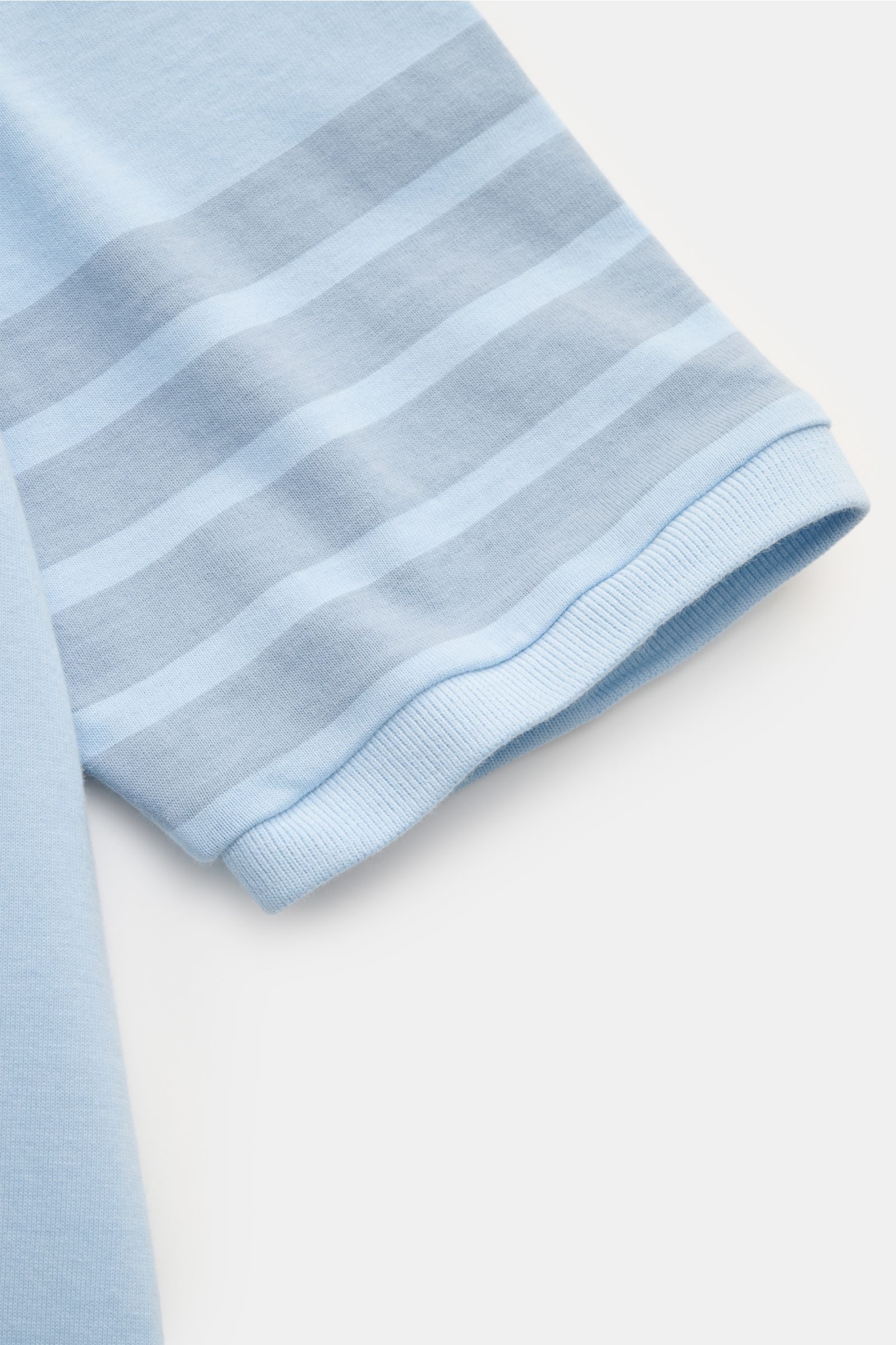 Close-up side view of the sleeve of the Thom Browne Crew neck T-shirt smoky blue, showing pure cotton fabric, soft feel, heavy fabric, slim fit, crew neck, wide hem, and signature stripes on the sleeves.

Monochrome T-shirt by THOM BROWNE in heavy pure