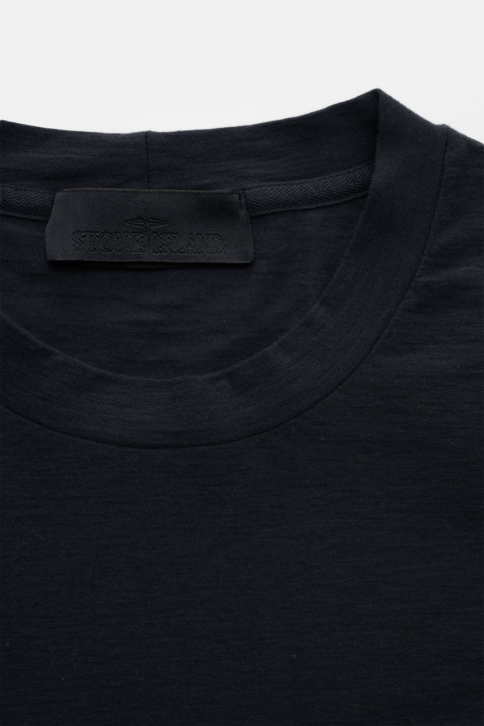 Stone Island Rundhals-T-Shirt 'Ghost Piece' navy aus elastischem Baumwolljersey, Slim Fit, garment dyed, mit tonalem Weblabel, Nahaufnahme von oben.