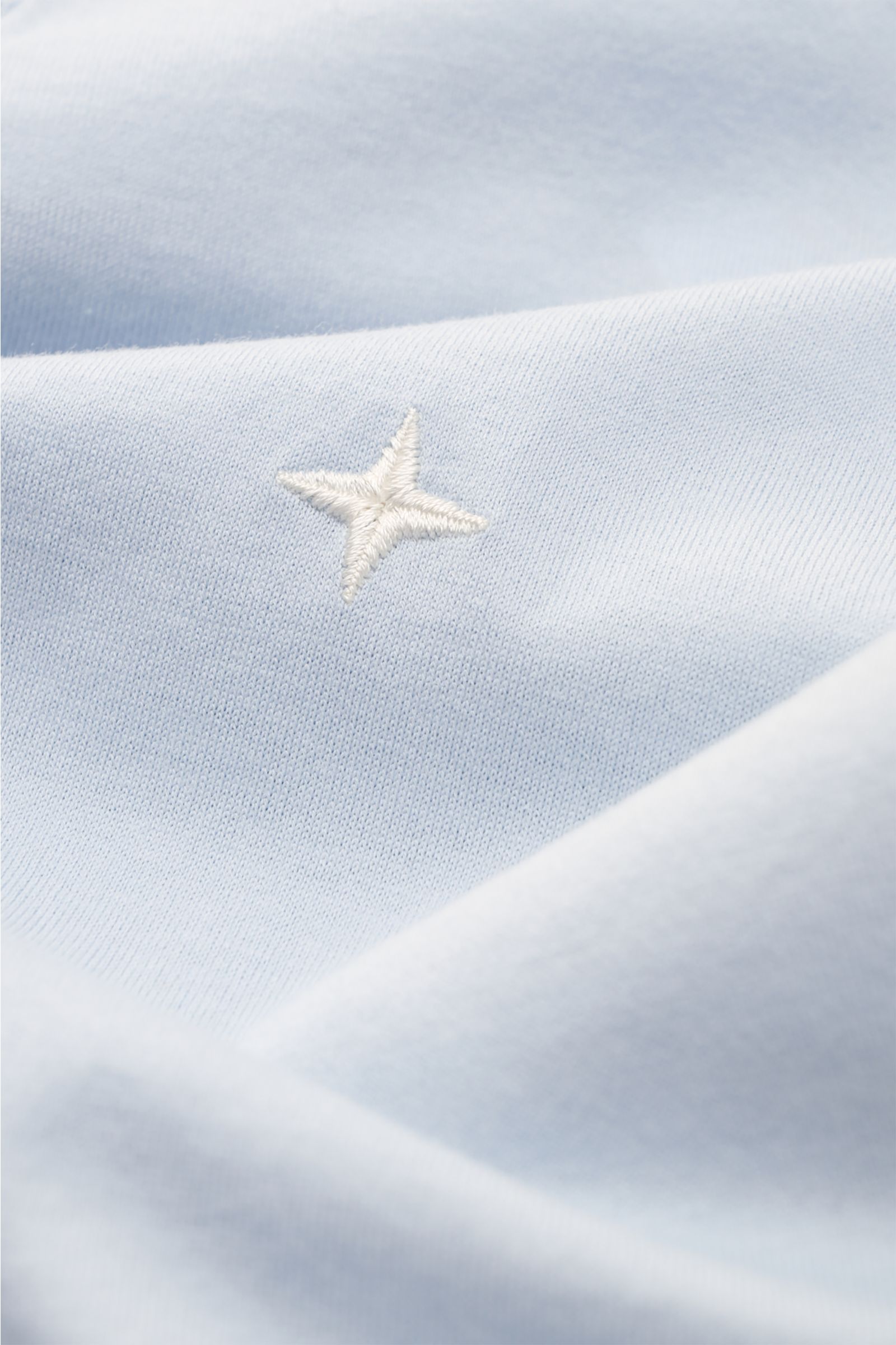 Close-up front view of Stone Island Crew neck T-shirt 'Stellina' pastel blue showing soft cotton jersey and subtle white star stitching.

Minimalist expression and precise workmanship: The T-shirt 'Stellina' from the Capsule Collection by STONE ISLAND 