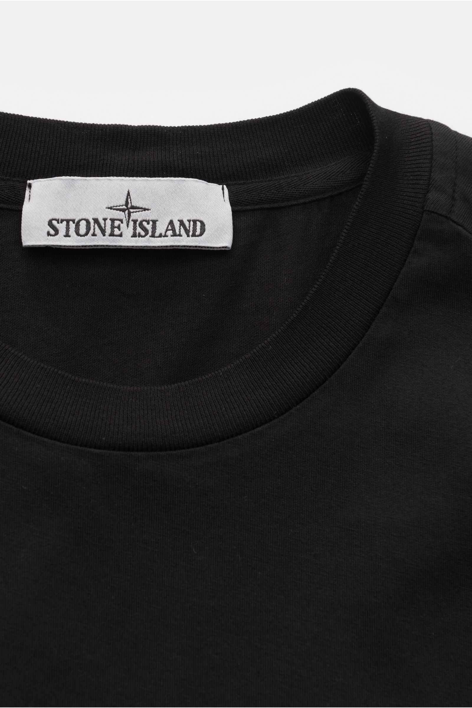 Alt-Tag (124 Zeichen): Nahaufnahme des schwarzen Stone Island T-Shirts 'Basic Cotton' mit Rundhalsausschnitt, Weblabel und weichem Baumwollstoff.