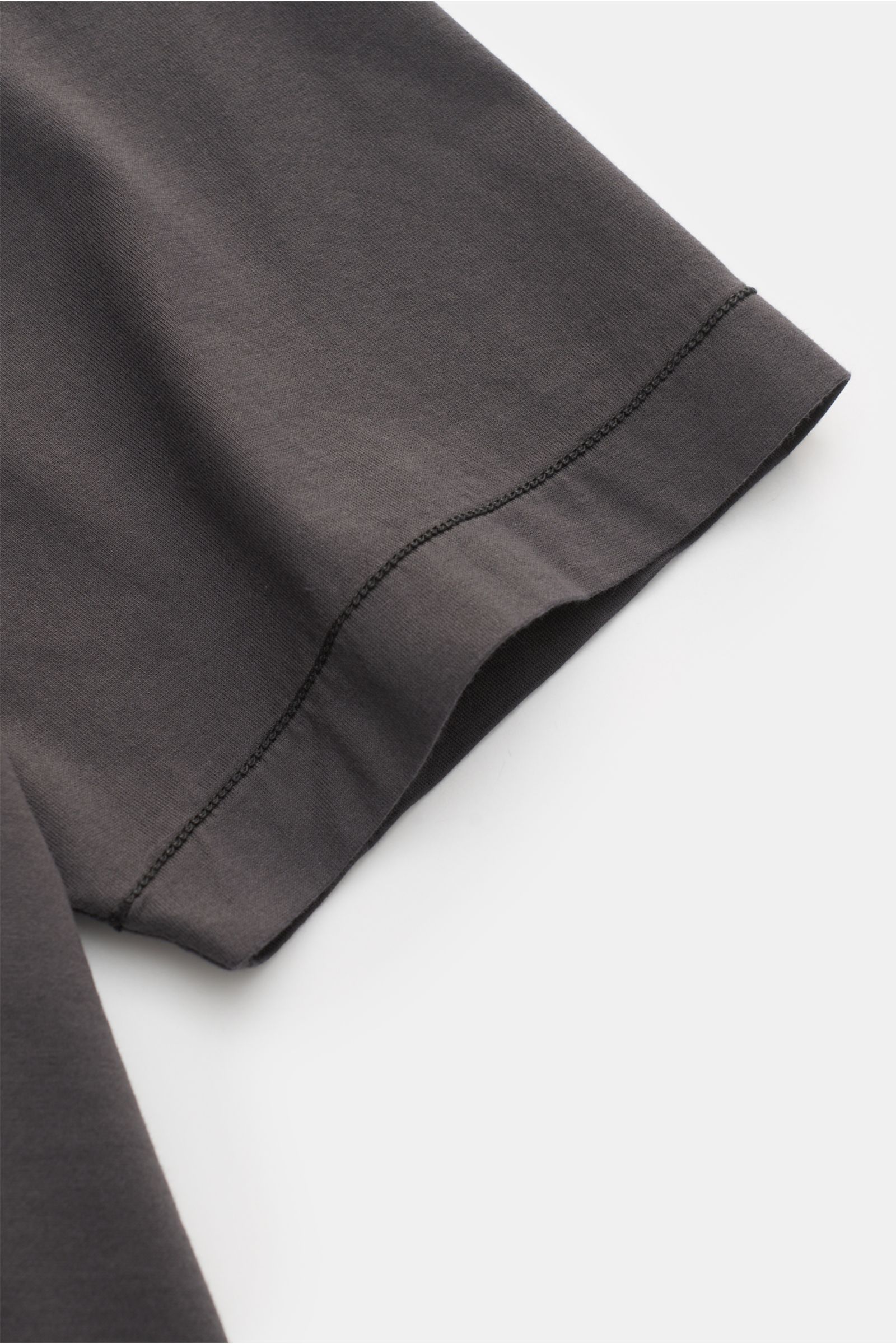 Nahaufnahme des Ärmels vom Stone Island T-Shirt 'Basic Cotton' dunkelgrau, reine Baumwolle, weicher Griff, Slim Fit, Rundhalsausschnitt, Weblabel auf der Brust, fotografiert von schräg oben.
