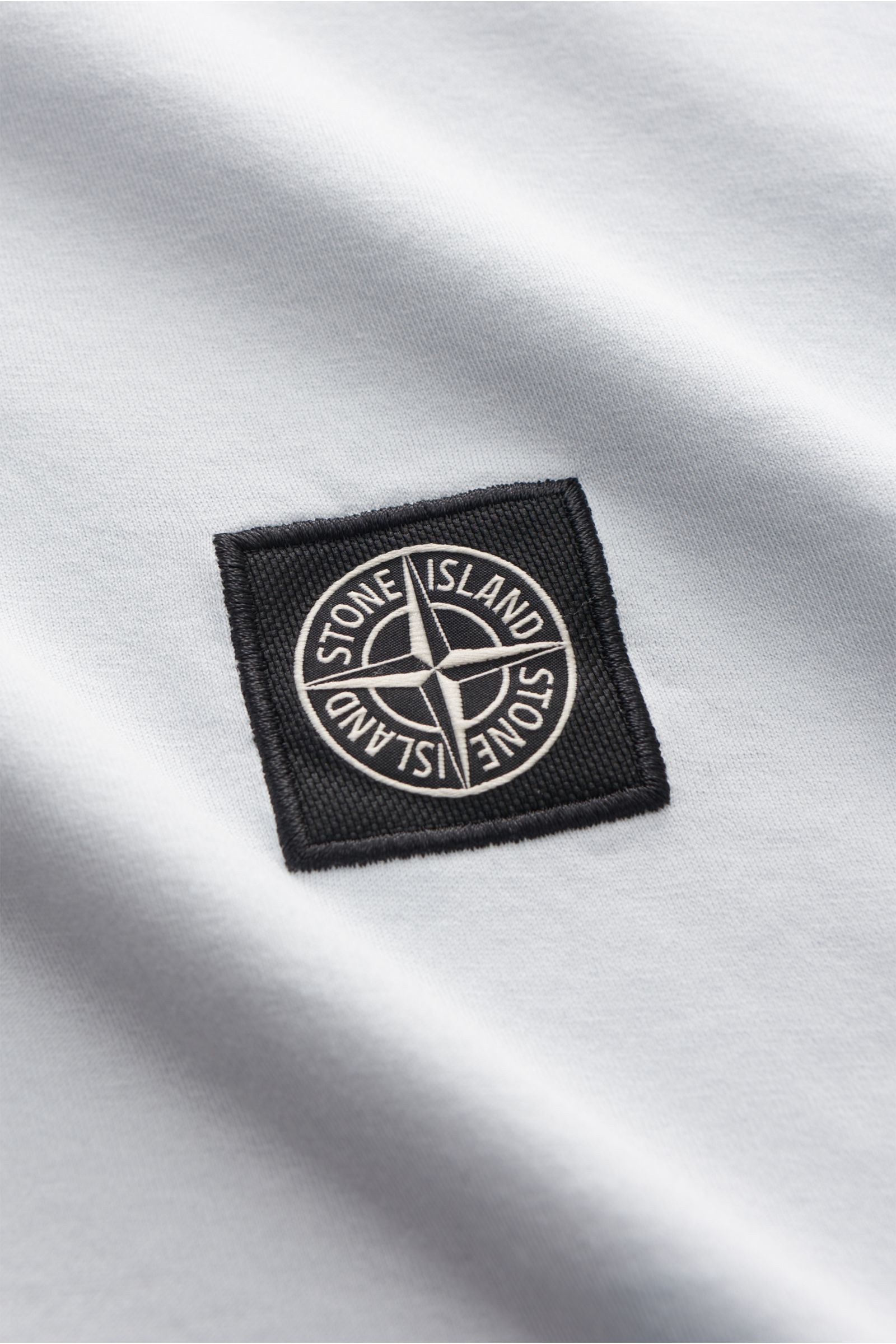 Stone Island T-Shirt 'Basic Cotton' pastellblau aus reiner Baumwolle mit weichem Griff, Slim Fit, Rundhalsausschnitt und Weblabel, Nahaufnahme auf Brust.