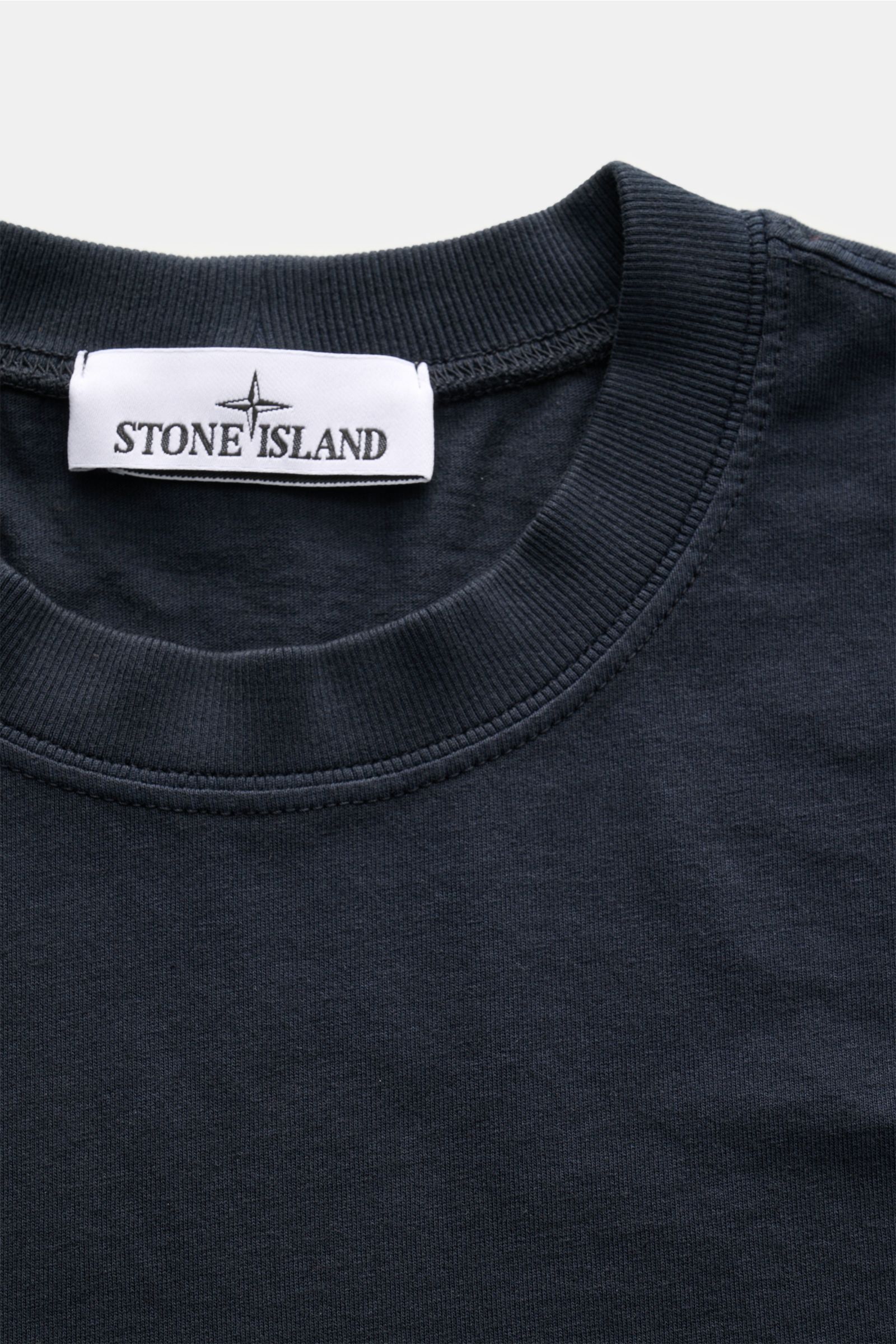 Stone Island T-Shirt 'Dyed Regular Fit' navy aus reiner Baumwolle, weicher Griff, Rundhalsausschnitt, Weblabel auf Brust, Nahaufnahme von oben.