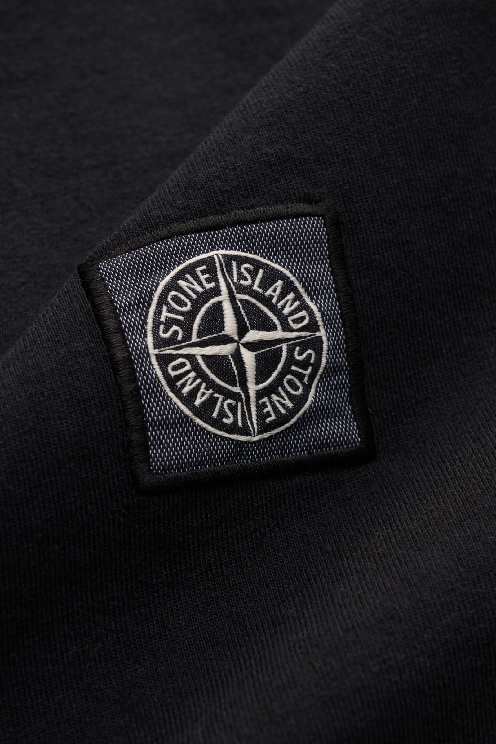 Nahaufnahme des Weblabels auf der Brust des Stone Island T-Shirts 'Dyed Regular Fit' schwarz aus reiner Baumwolle, weicher Griff, Regular Fit, Rundhalsausschnitt.