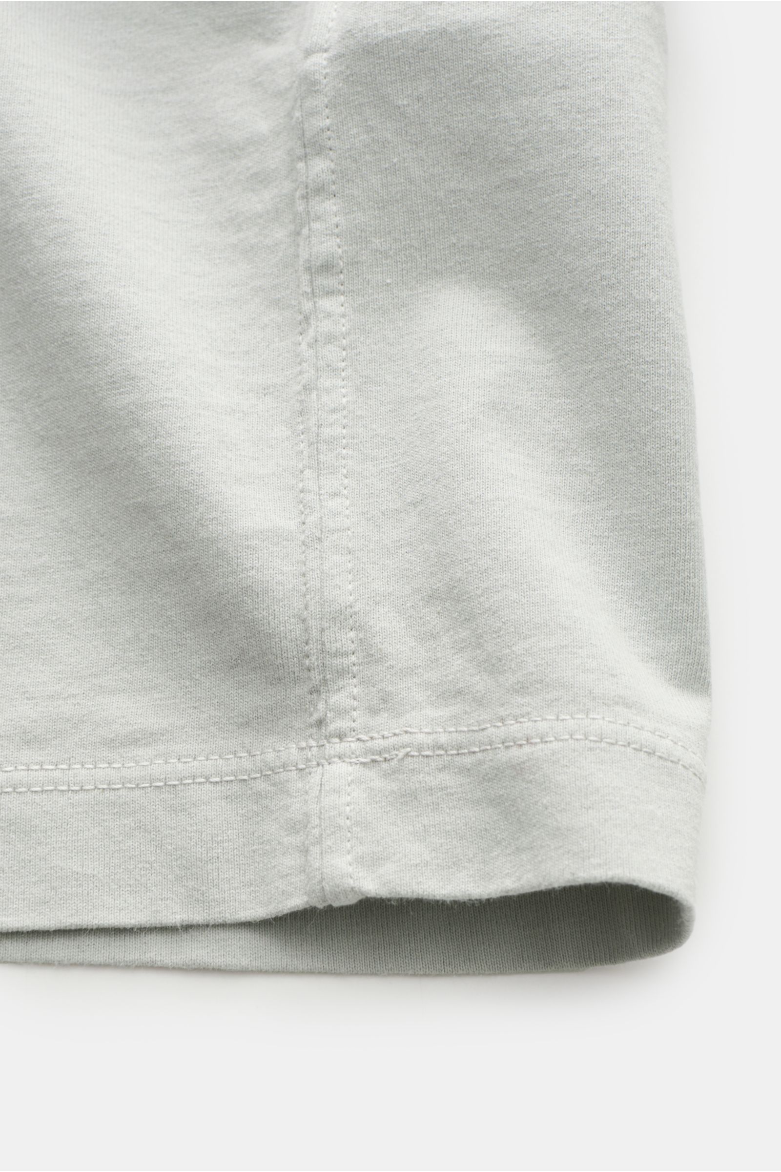 Close-up side view of Stone Island Rundhals-T-Shirt hellgrau showing garment-dyed cotton jersey with lightly textured feel, distinct overlock seams, short cut, regular fit, round neckline, and STONE ISLAND web label.

STONE ISLAND liefert mit diesem le