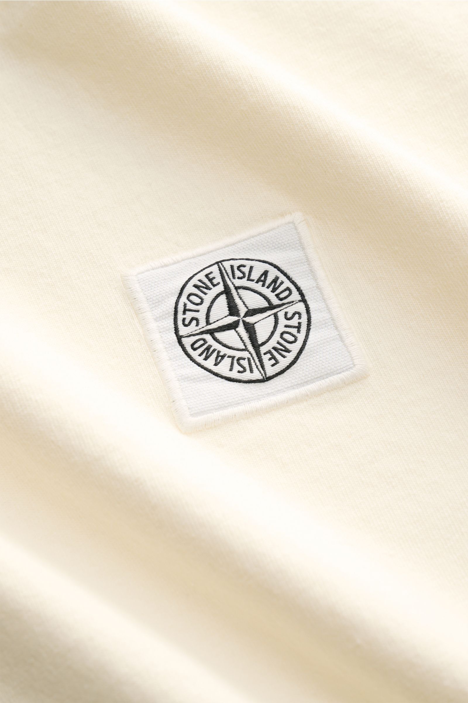 Stone Island T-Shirt 'Dyed Regular Fit' creme aus reiner Baumwolle mit weichem Griff, Rundhalsausschnitt, Weblabel auf der Brust, Detailfoto.