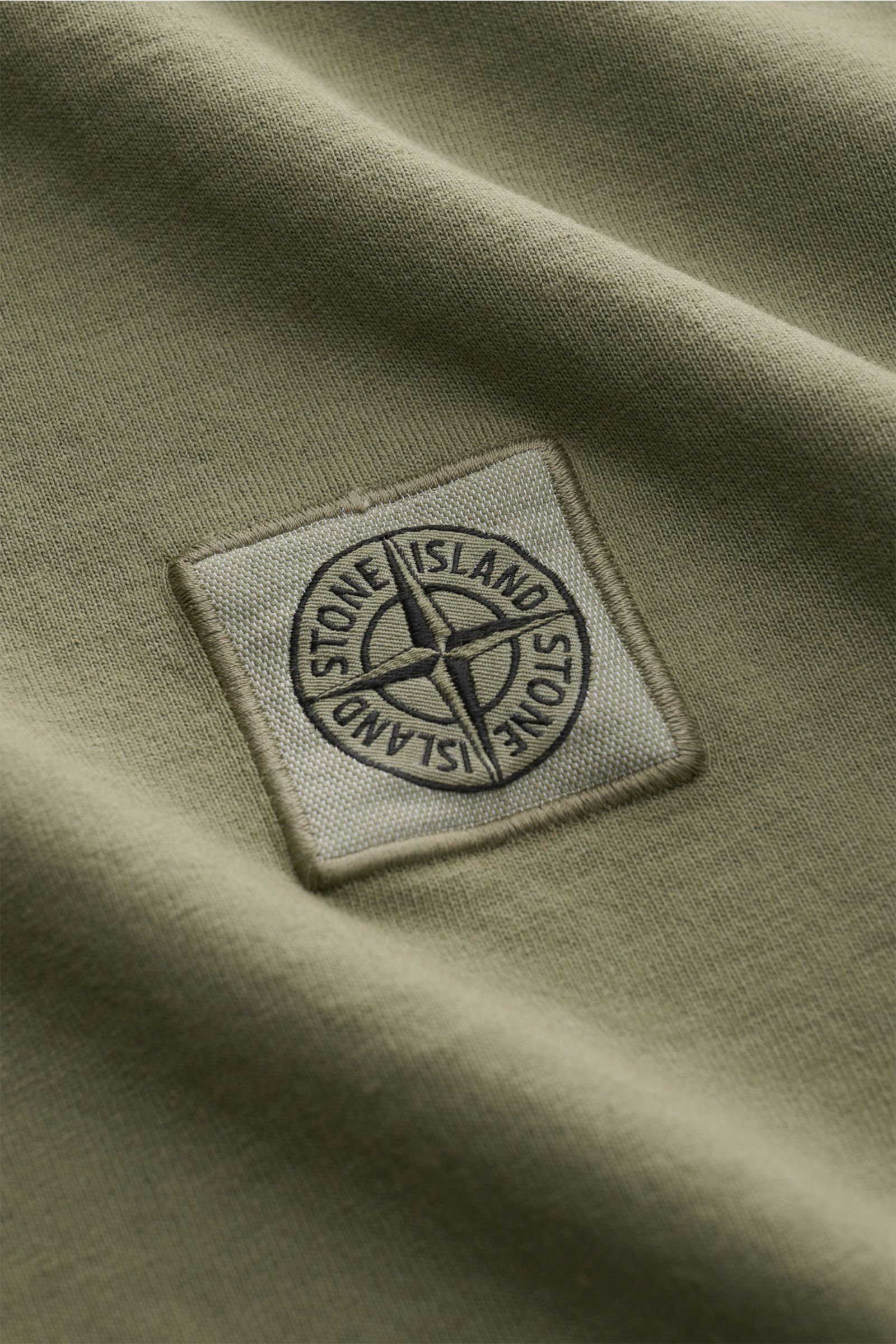 Close-up front view of Stone Island T-shirt 'Dyed Regular Fit' olive showing woven label on chest in pure organic cotton fabric.

A timeless basic piece: This T-shirt by STONE ISLAND in pure organic cotton effortlessly completes relaxed casual looks an