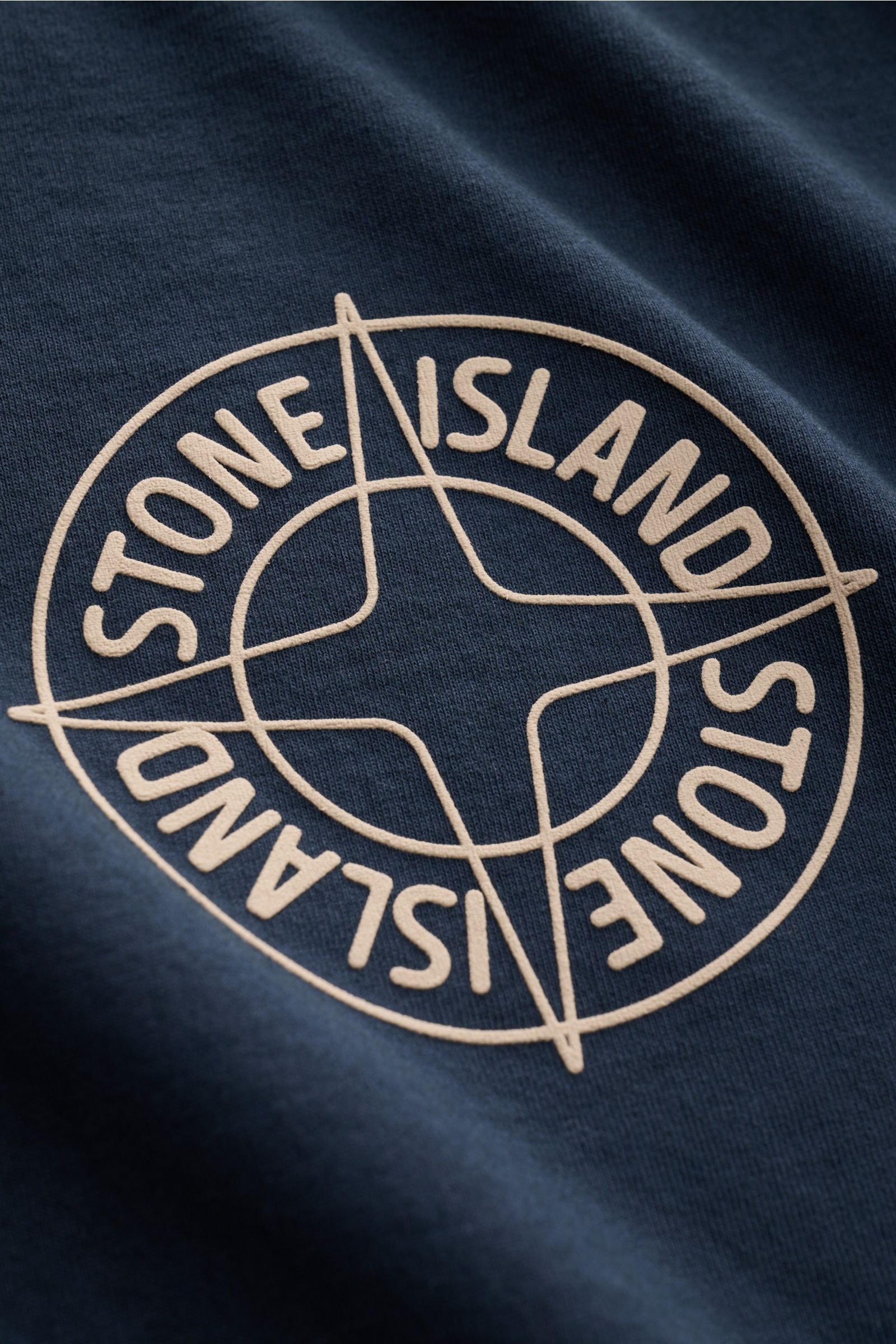 Close-up front view of the Stone Island T-Shirt 'Print' navy showing the beige logo print on navy fabric.

Eyecatcher mit Print: Das T-Shirt von STONE ISLAND aus reiner Bio-Baumwolle rundet legere Freizeitlooks mühelos ab und wird zum vielseitigen Allr