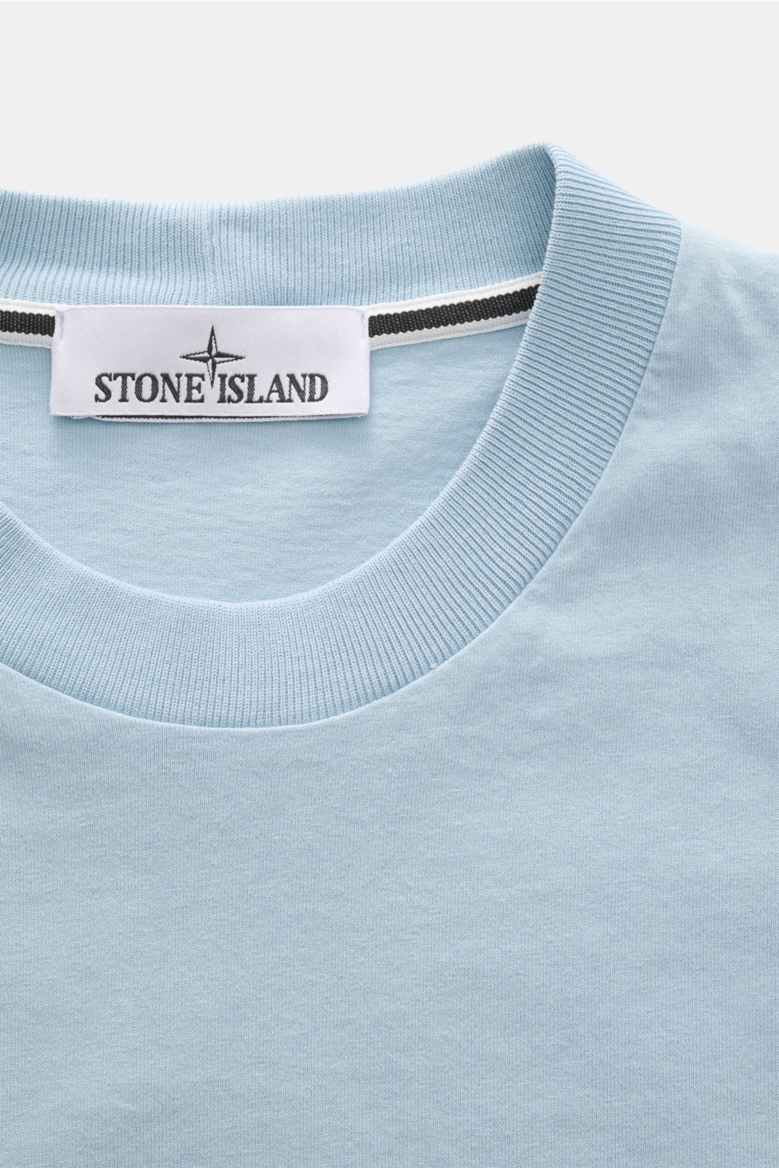 Stone Island Rundhals-T-Shirt hellblau in Nahaufnahme von oben, weicher Baumwoll-Jersey, Regular Fit, Front- und Rückenprint sichtbar.