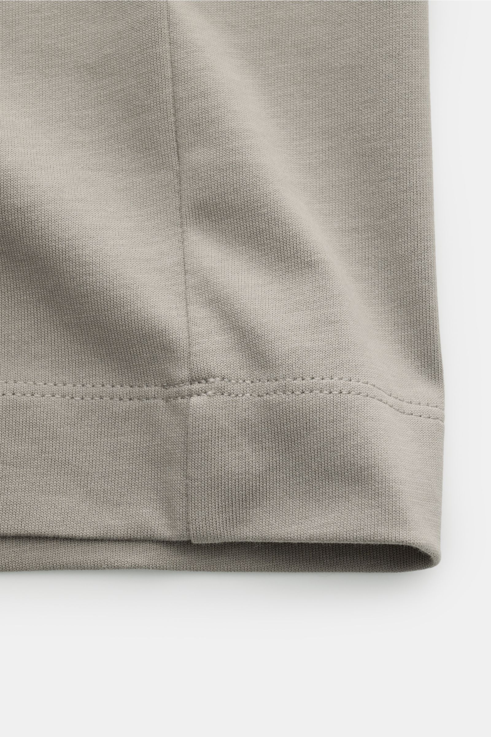 Nahaufnahme des Saums eines taupefarbenen Emporio Armani Rundhals-T-Shirts aus schwerem Baumwoll-Jersey mit sichtbarem Stitching.