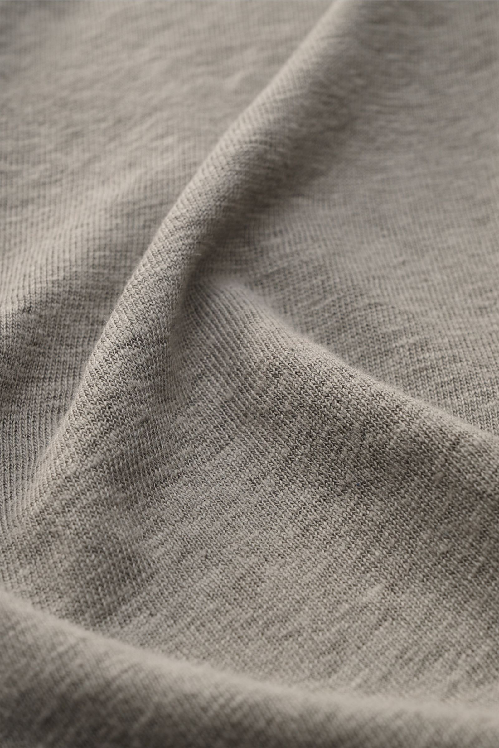 Close-up image of the fabric texture of the 04651/ A trip in a bag Leinen-T-Shirt grau, showing a grey linen jersey with a slightly textured, airy quality, light stretch, photographed from a top-front perspective. Jersey aus Leinenleicht 