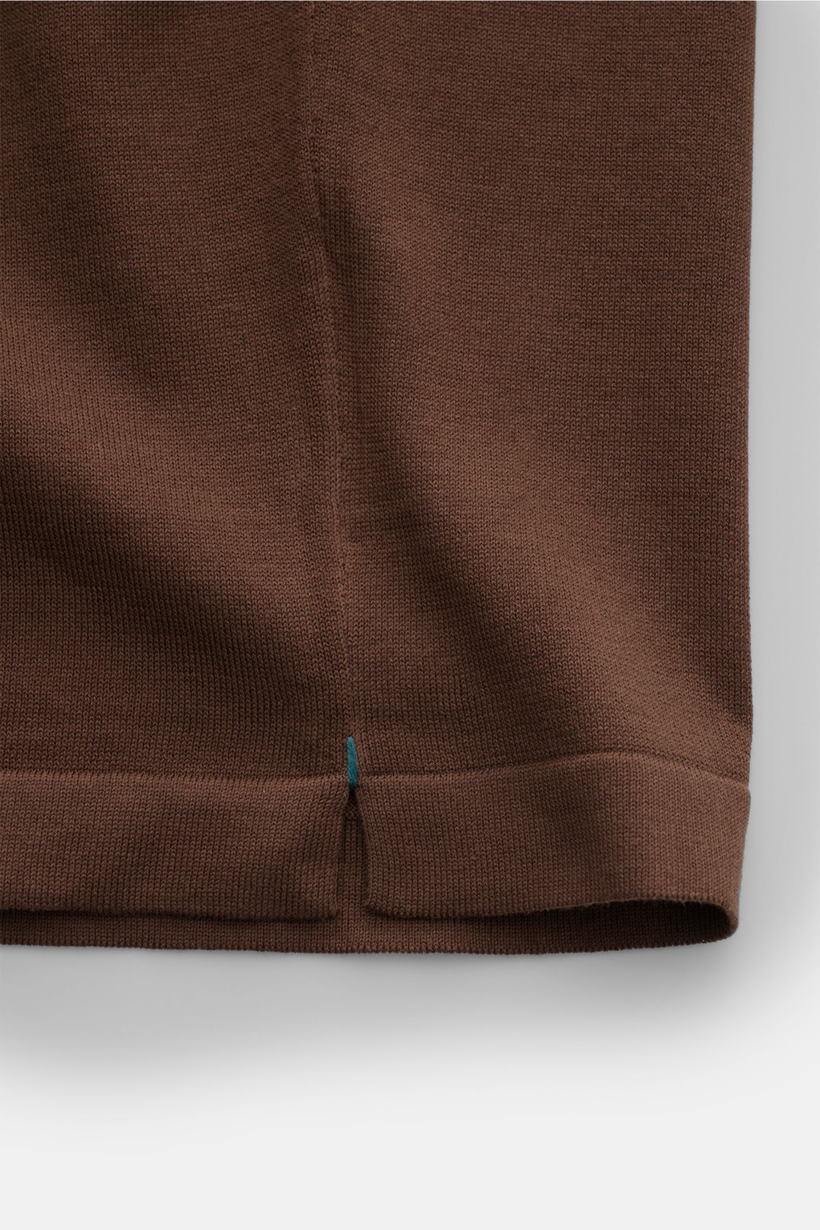 Nahaufnahme des unteren Saums vom braunen Fioroni Rundhals-T-Shirt, fein gestrickt aus reiner Baumwolle mit kurzen Saumschlitzen.