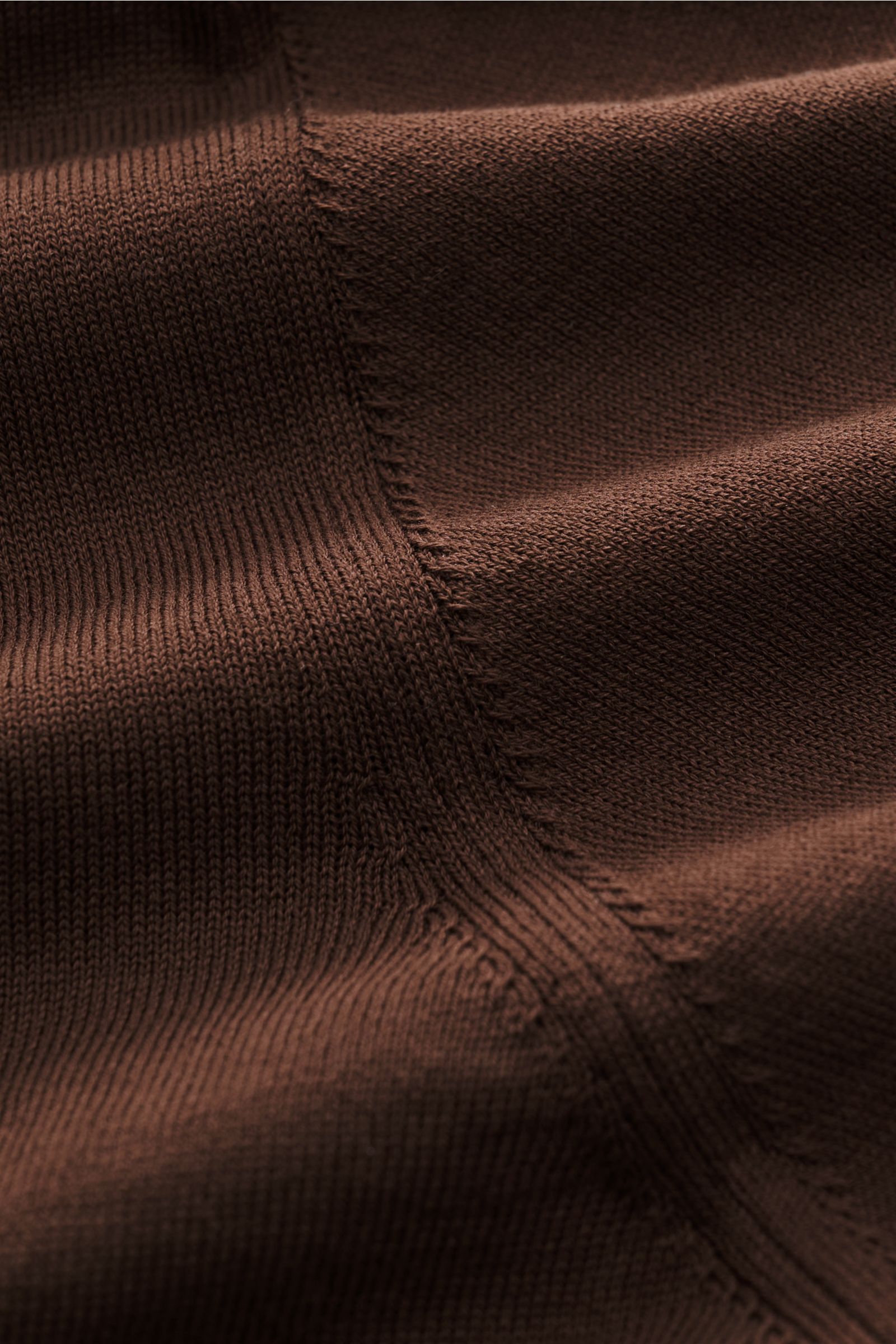 Nahaufnahme des fein gestrickten, braunen Fioroni Rundhals-T-Shirts aus reiner Baumwolle mit handgemachten Stitchings, weichem Griff, Slim Fit, Rundhalsausschnitt und kurzen Saumschlitzen, fotografiert aus schräger Perspektive.