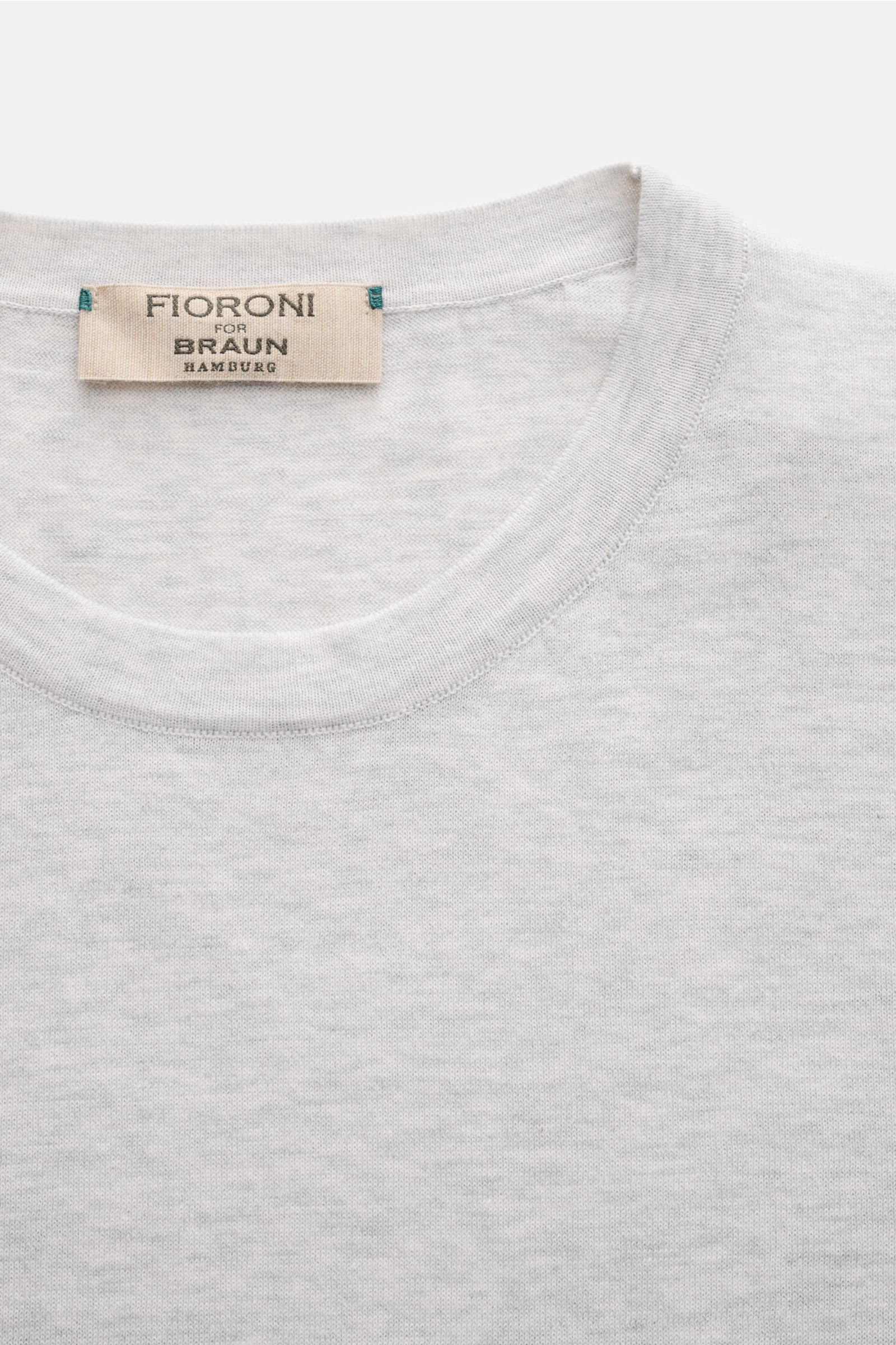 Close-up front view of Fioroni Rundhals-T-Shirt hellgrau meliert showing light gray fine knit fabric with round neckline and label.

Für den gediegenen Auftritt im Frühling sorgt dieses fein gestrickte T-Shirt von FIORINI, welches aus reiner Baumwolle 