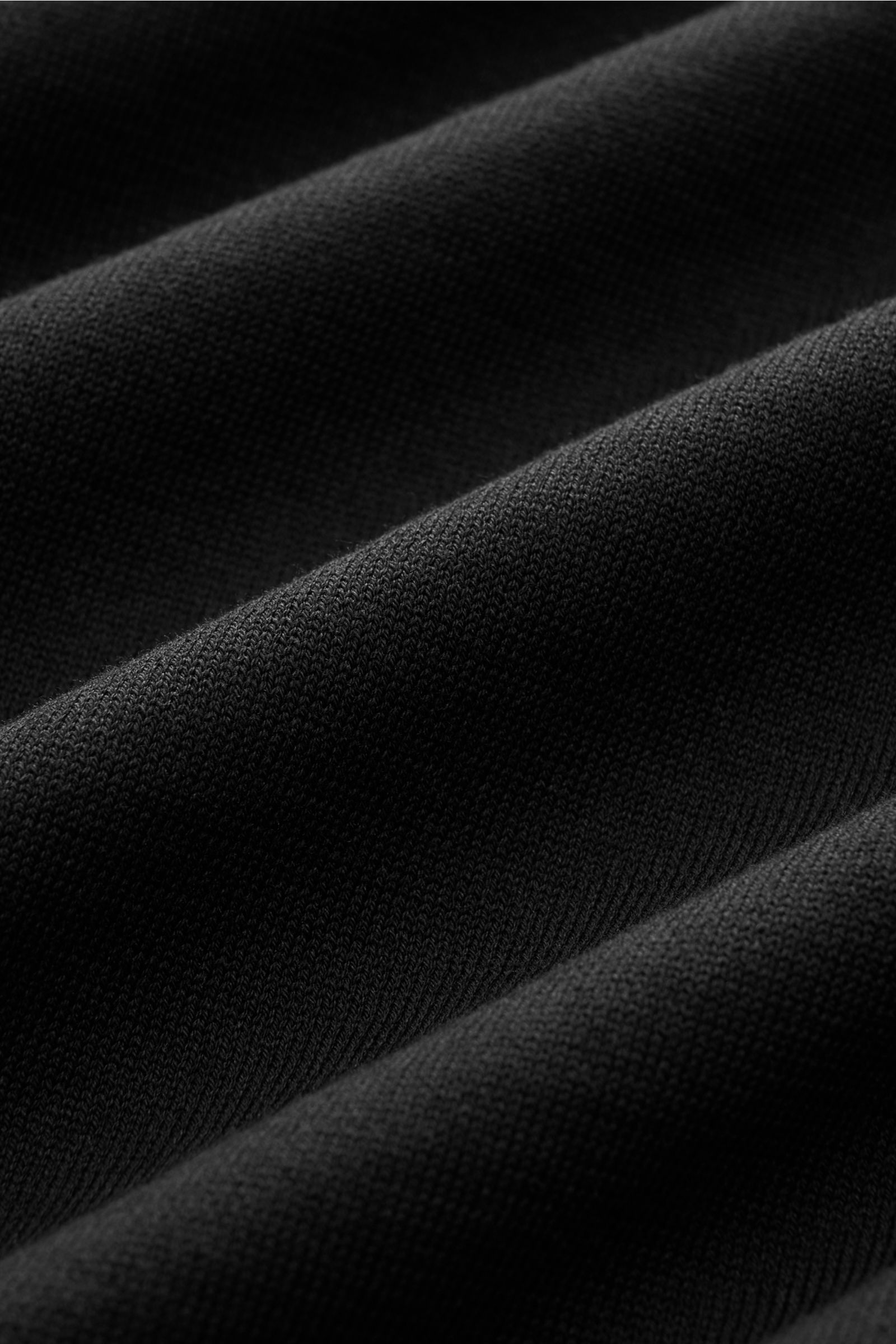 Nahaufnahme des fein gestrickten schwarzen Stoffes des Fioroni Rundhals-T-Shirts schwarz aus reiner Baumwolle mit weichem Griff.