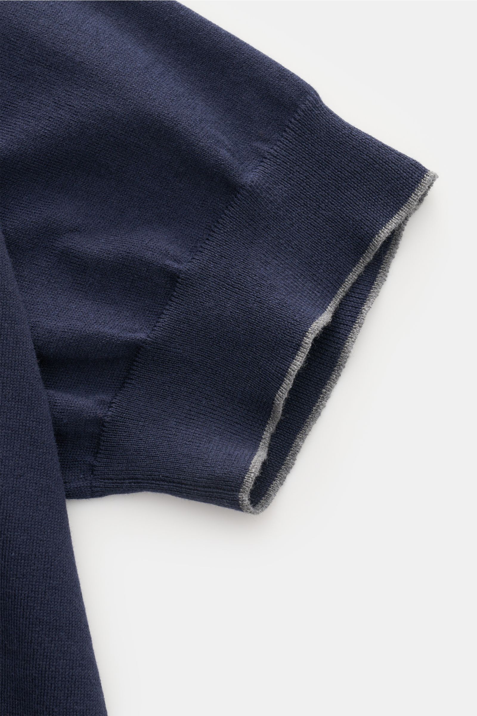Brunello Cucinelli Kurzarmpullover navy, Detailaufnahme Ärmelsaum mit schmalen Kontrastkanten, feiner Baumwollstrick, Slim Fit, von oben fotografiert.