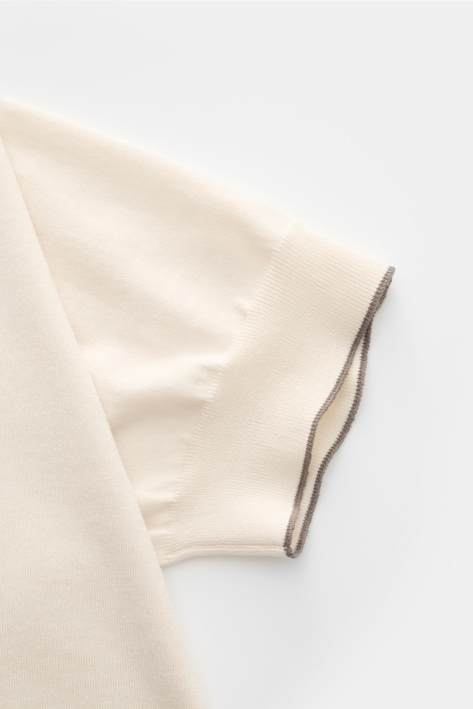 Close-up side view of the sleeve of the Brunello Cucinelli Kurzarmpullover creme, a slim fit, pure cotton knit with fine texture and narrow contrast edges.

Dieser zeitlose, vielseitige Kurzarmpullover von BRUNELLO CUCINELLI aus reiner Baumwolle in fei