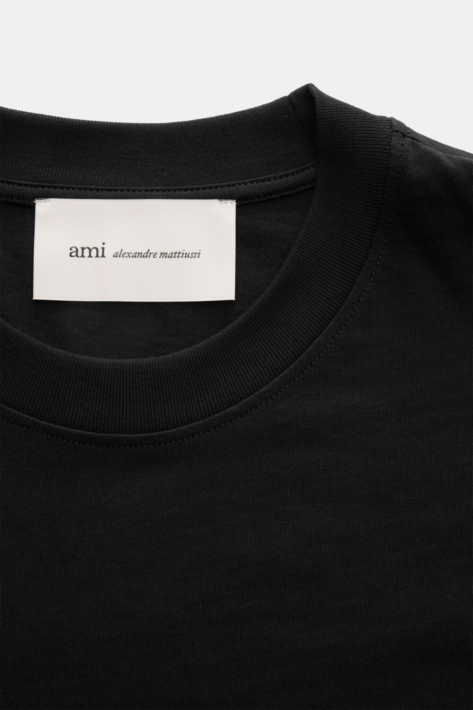 Nahaufnahme des schwarzen Ami Paris Rundhals-T-Shirts aus Jersey-Baumwolle mit Rundhalsausschnitt, weichem Griff und sichtbarem Label innen am Kragen.