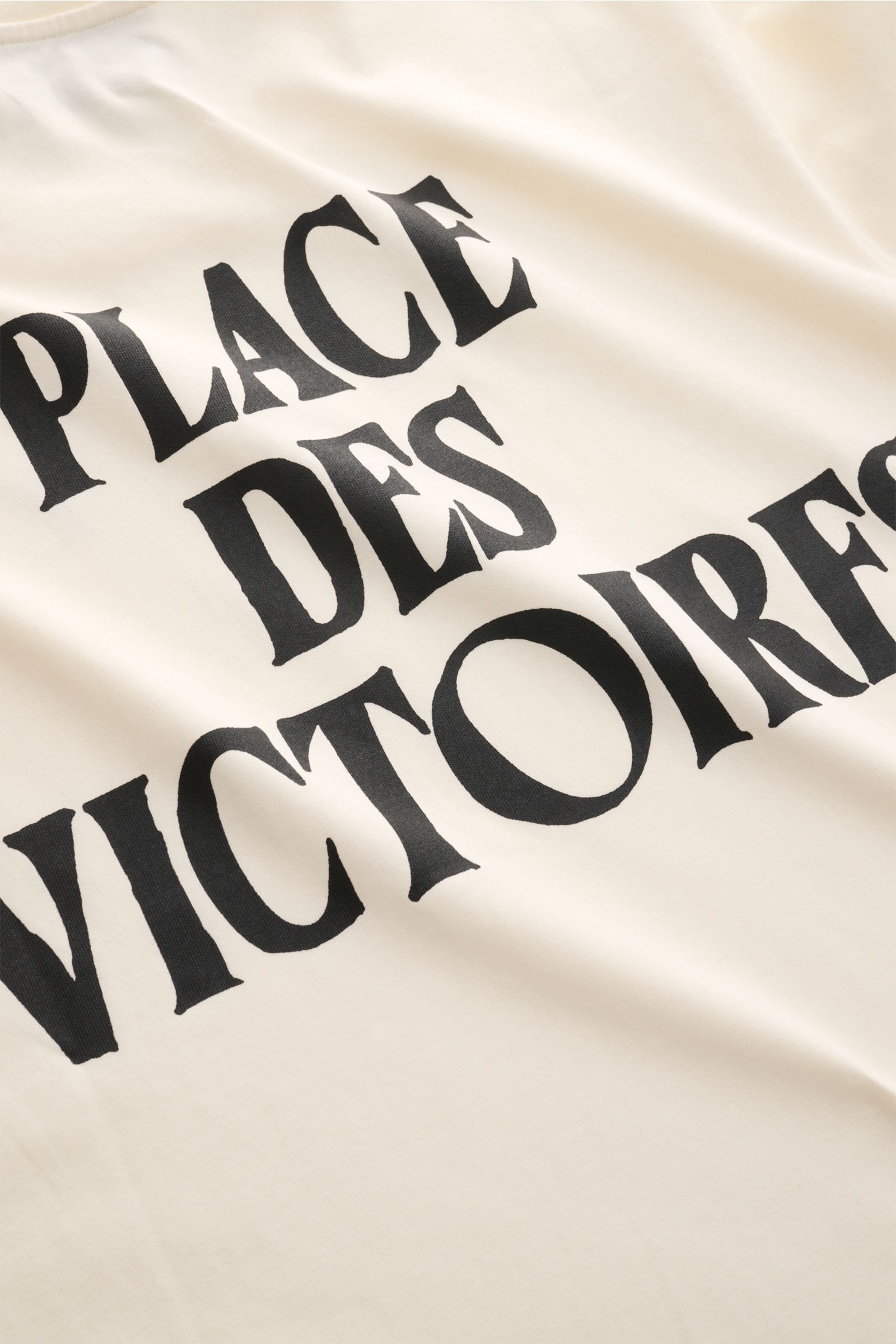 Close-up front view of Ami Paris Rundhals-T-Shirt creme showing black 'PLACE DES VICTOIRES' print on soft, creamy organic cotton fabric.

Monochromes Jersey-Basic vom französischen Label AMI PARIS: Dieses T-Shirt mit Rundhalsausschnitt ist aus reiner B