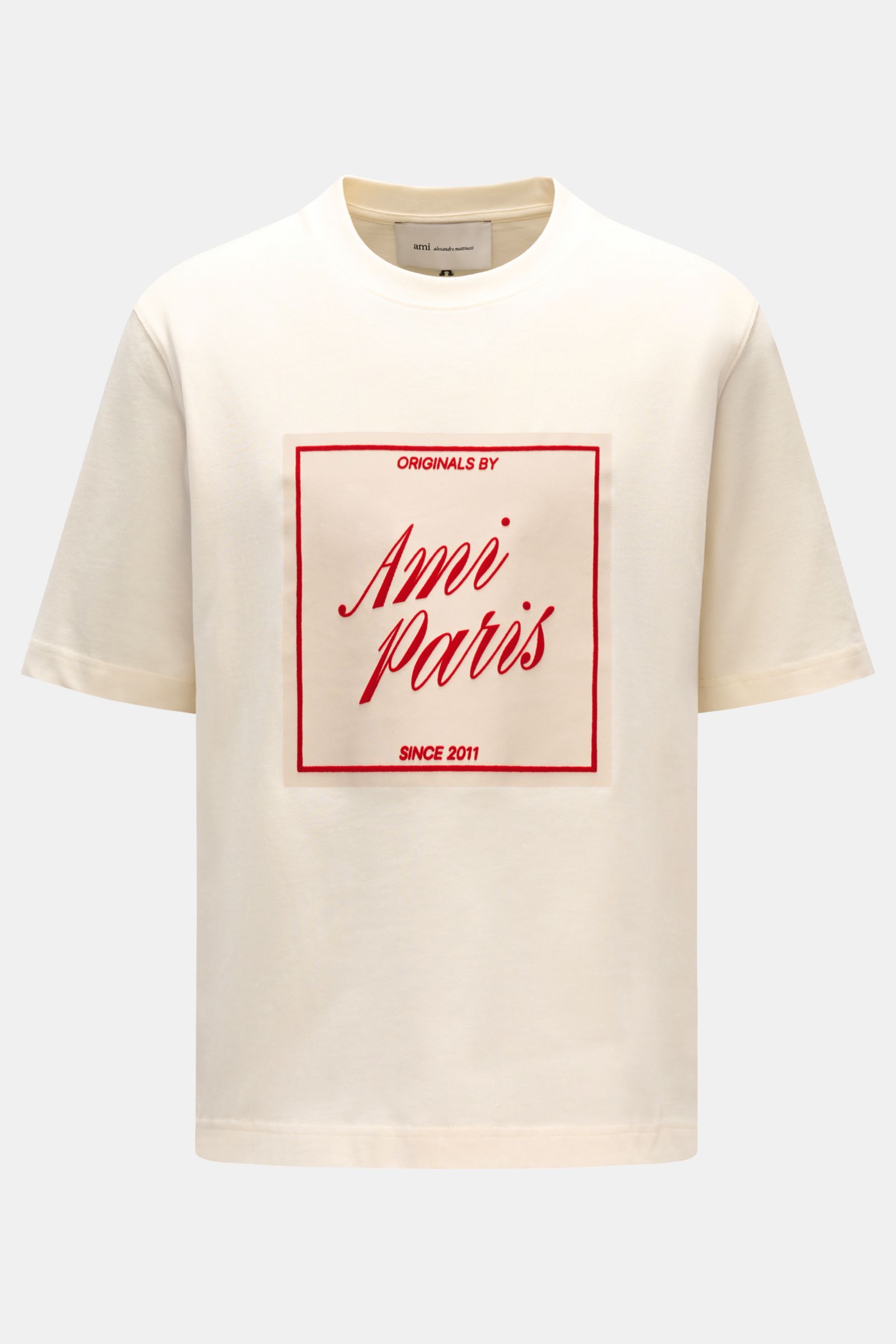 Ami Paris Rundhals-T-Shirt creme, frontal fotografiert, aus reiner Baumwolle, Regular Fit, weicher Griff, geflockter roter AMI PARIS-Schriftzug, Rundhalsausschnitt.