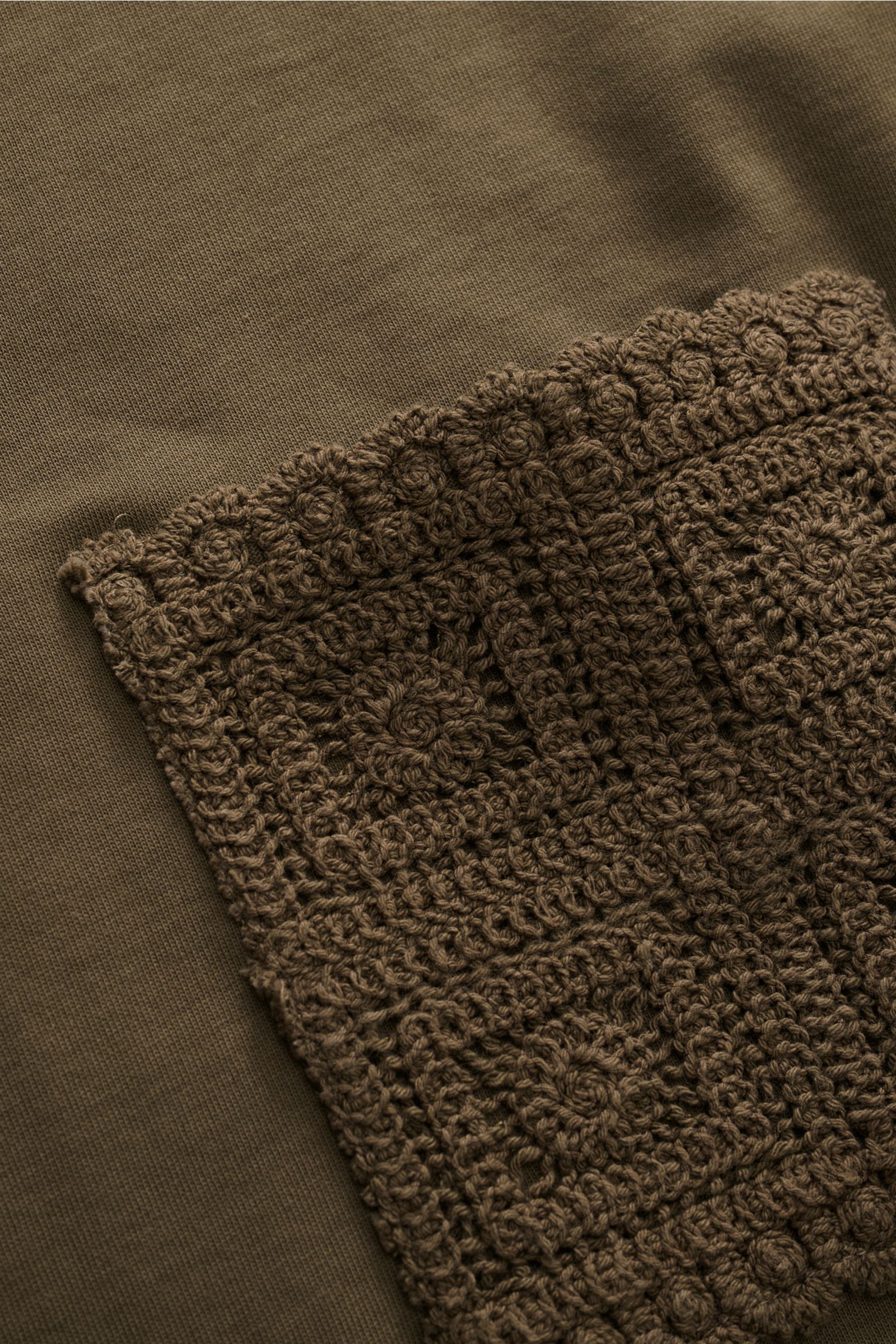 Close-up of the crochet hem detail on the Ché T-Shirt 'Inigo' dark olive, photographed from above to show texture and fabric.

Description: Sommerliche Lässigkeit: Die Das 'Inigo' T-Shirt von CHÉ wird mit seinen Häkel-Details zum stilvollen Blickfang f