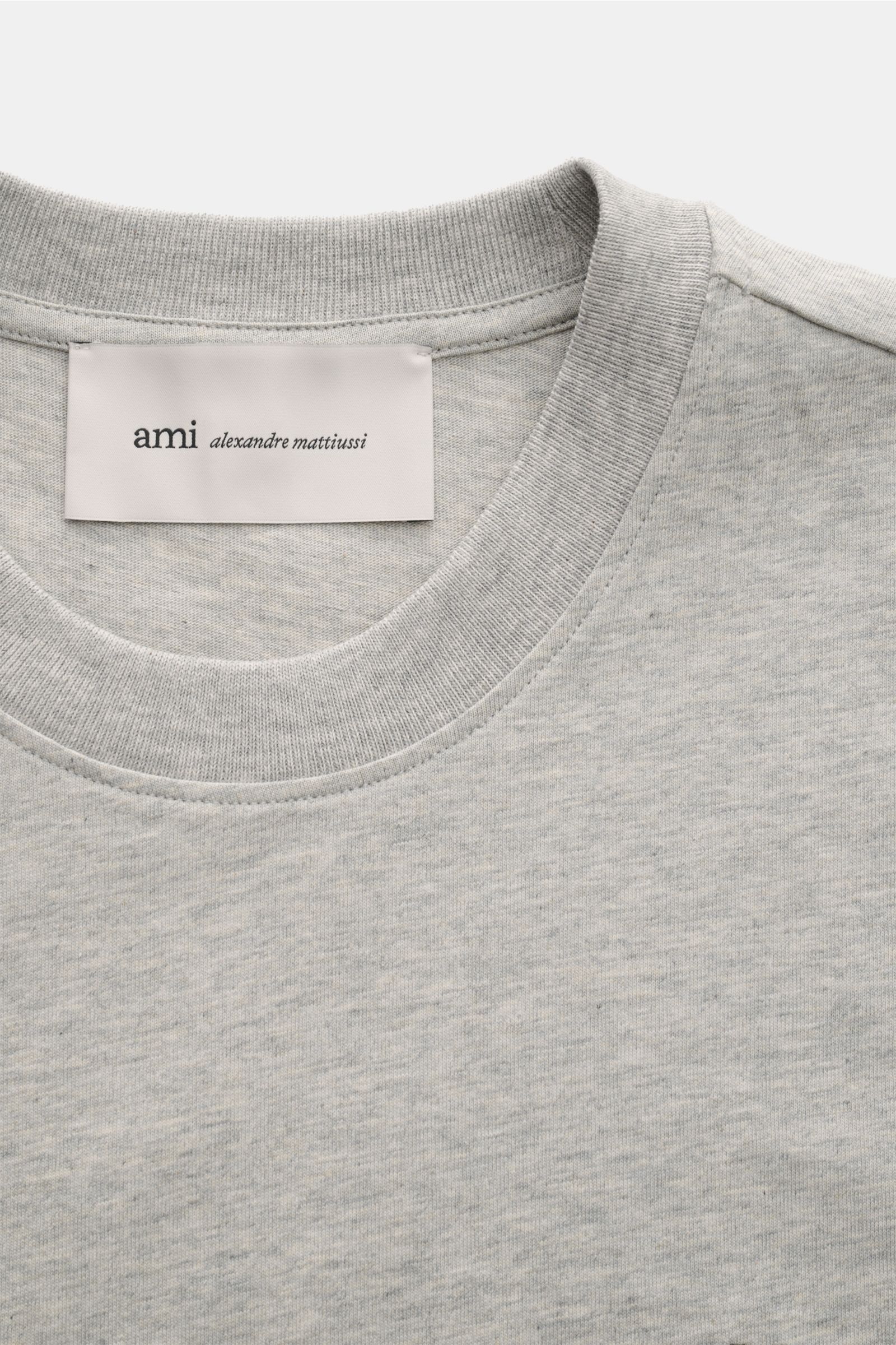Close-up front view of Ami Paris Rundhals-T-Shirt grau meliert showing classic round neckline, soft grey melange cotton jersey, and label.

Description: Klassisches Jersey-Basic vom französischen Label AMI PARIS: Dieses T-Shirt mit Rundhalsausschnitt i