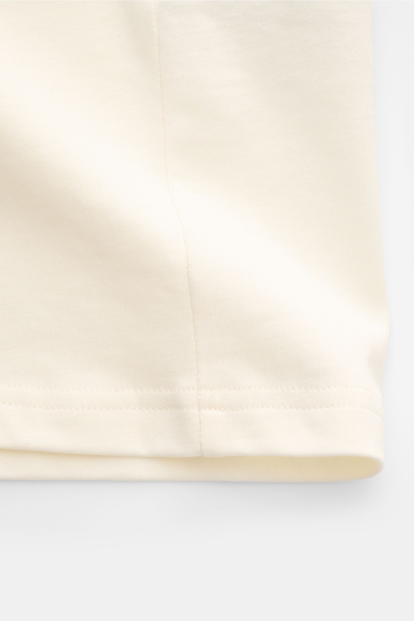 Nahe Aufnahme des unteren Saums eines Ami Paris T-Shirts 'Boxy Fit' creme/schwarz, reine Baumwolle, Oversized Fit, Raglanärmel.