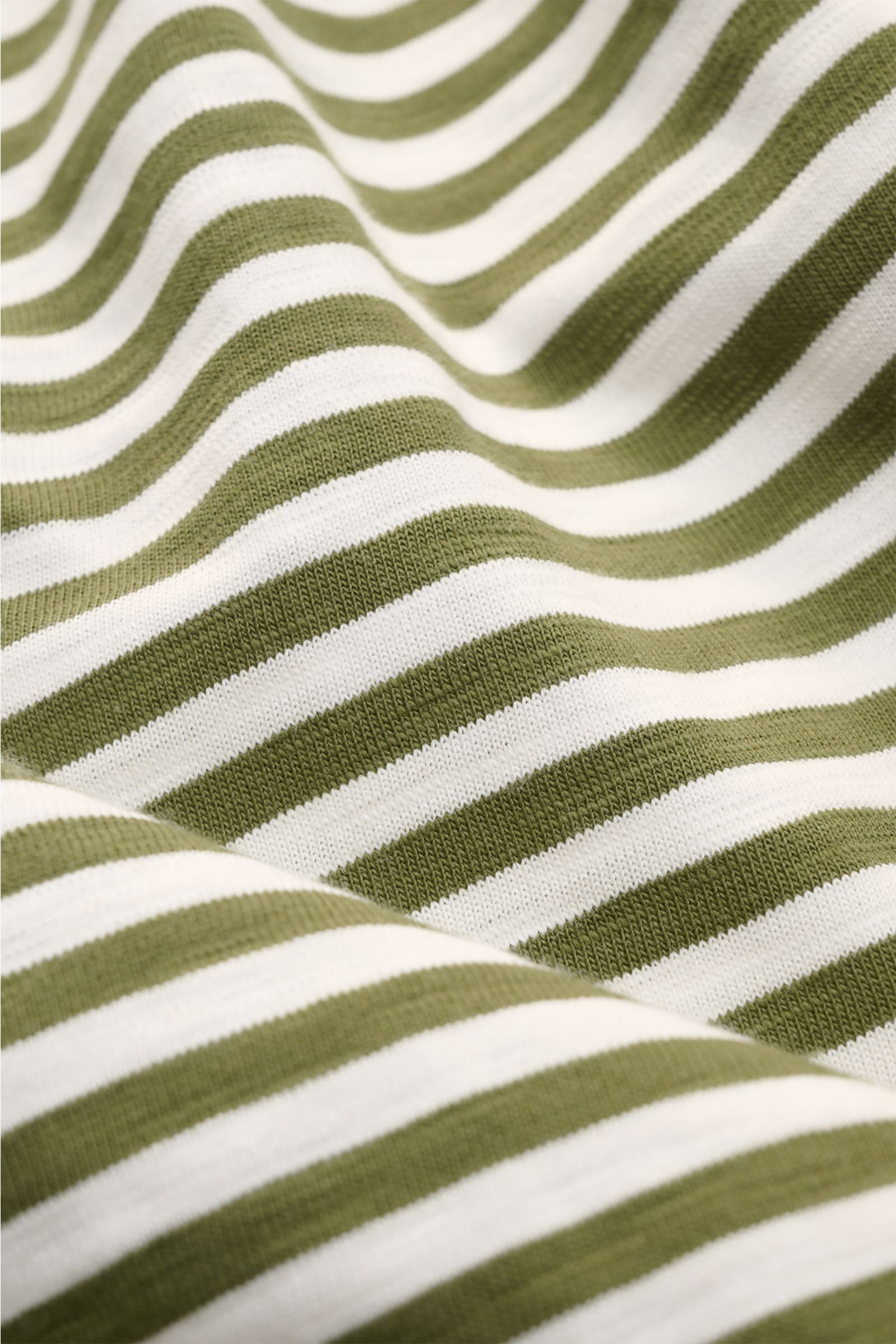 Close-up front view of the striped fabric of the Closed Rundhals-T-Shirt oliv/offwhite gestreift, showing olive and offwhite knitted stripes made from soft, pure organic cotton with a slim fit, round neckline, and short side slits, embodying urban streets