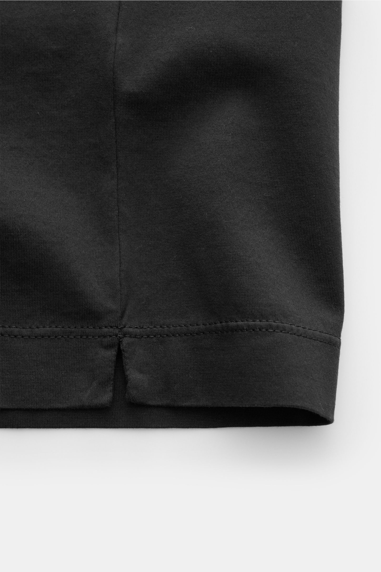 Nahaufnahme des unteren Saums eines schwarzen C.P. Company Rundhals-T-Shirts mit weichem Griff aus mercerisierter Baumwolle.