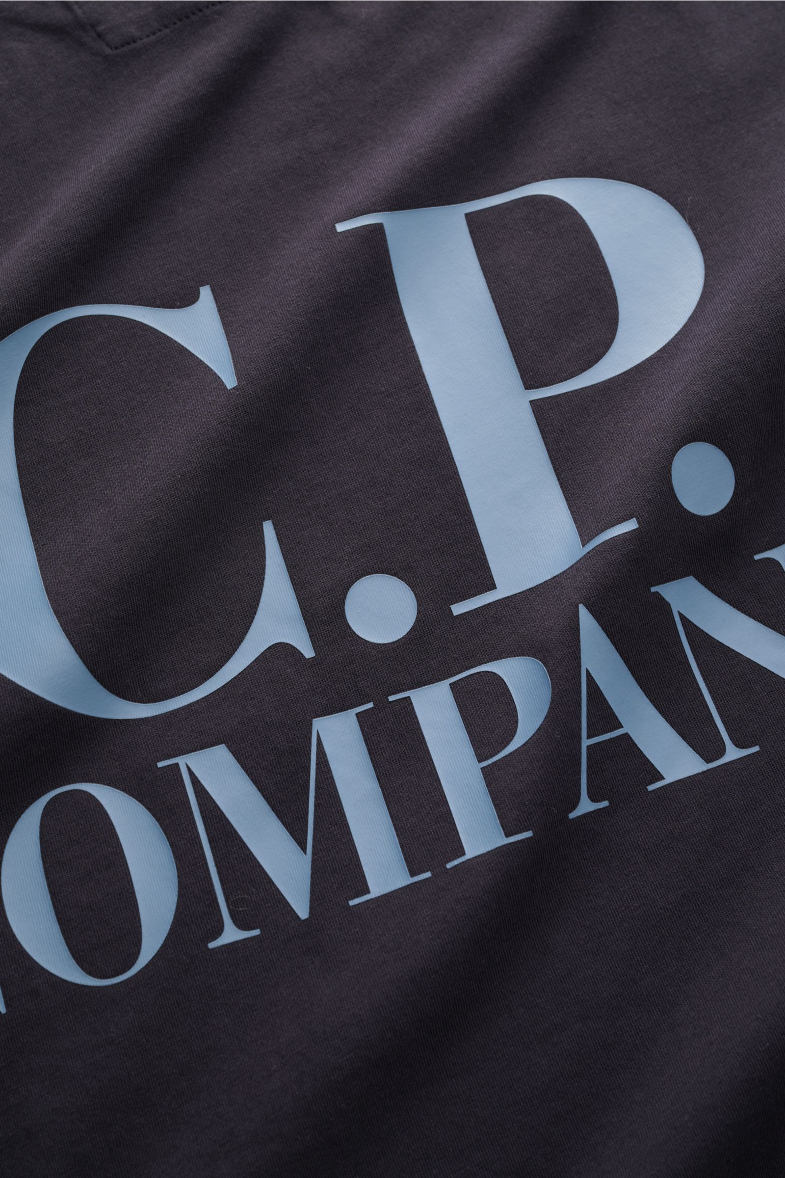 Nahaufnahme des dunkelblauen C.P. Company T-Shirt dark navy mit großem hellblauen Logo-Print, reine Baumwolle, weicher Griff.