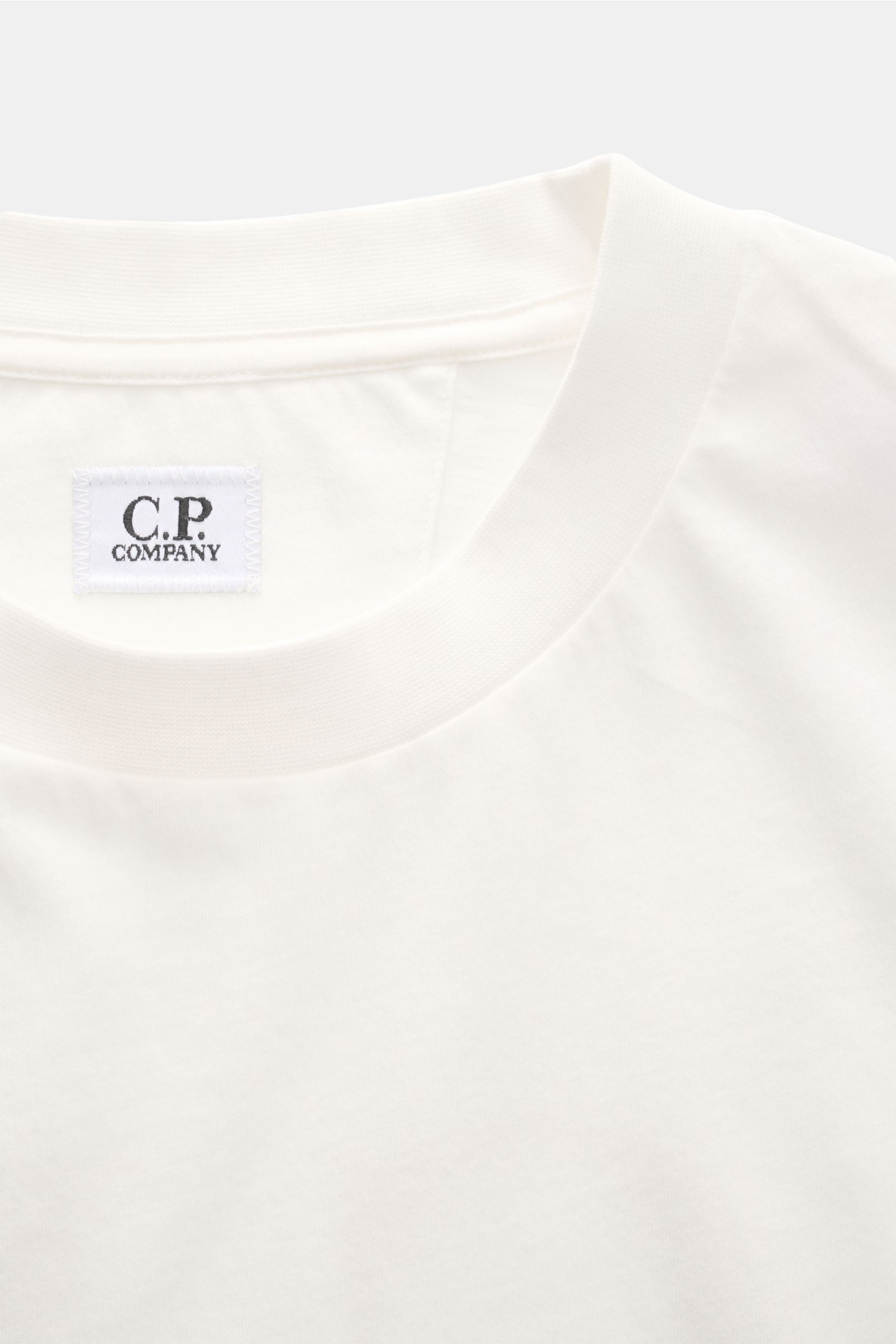 C.P. Company T-Shirt offwhite in Nahaufnahme von oben, reine Baumwolle, weicher Griff, Slim Fit, Rundhalsausschnitt, Logo-Print Brust, großer Backprint.