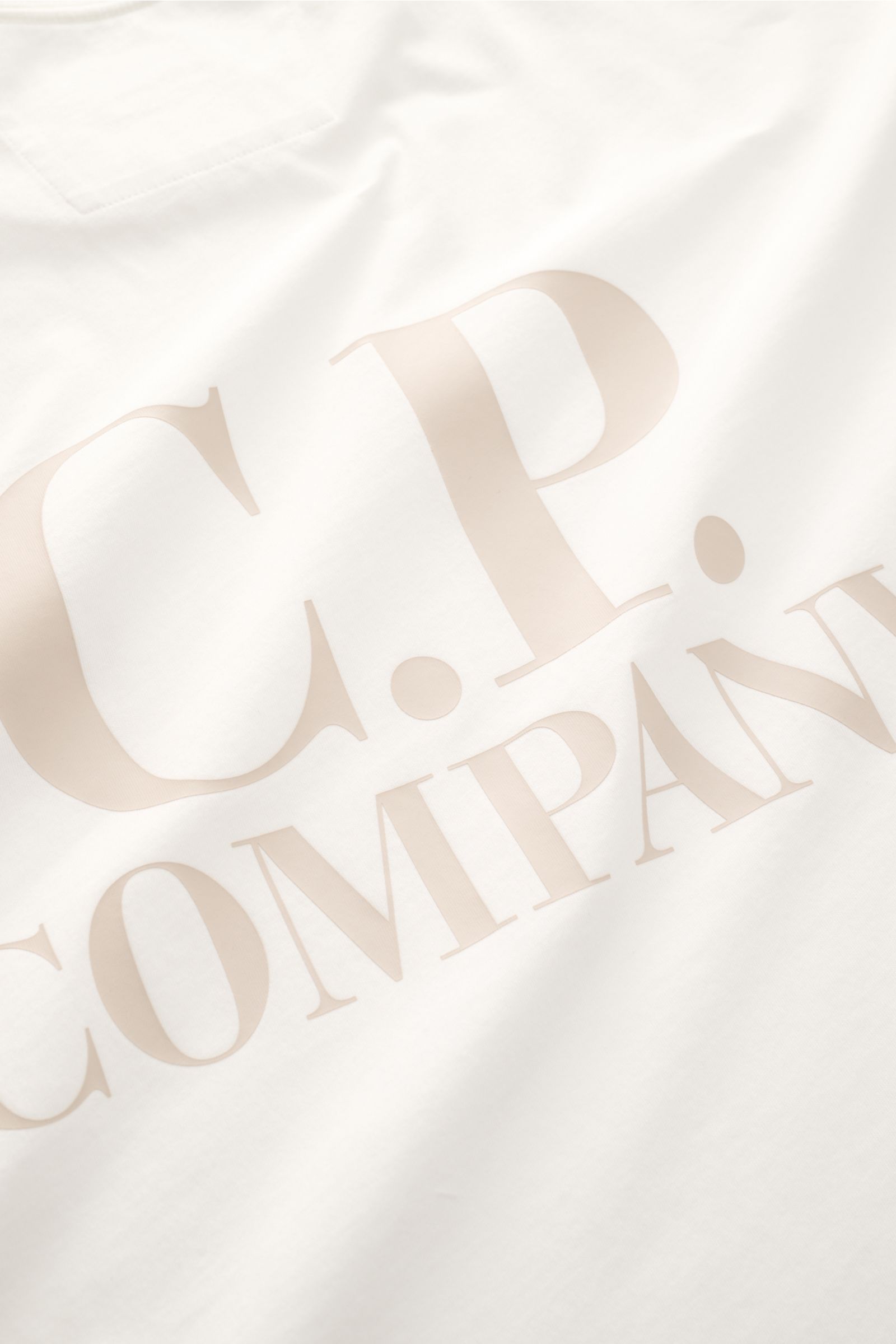 C.P. Company T-Shirt offwhite in Slim Fit, reine Baumwolle, weicher Griff, Rundhalsausschnitt, Logo-Print auf Brust, großer Backprint, Nahaufnahme.