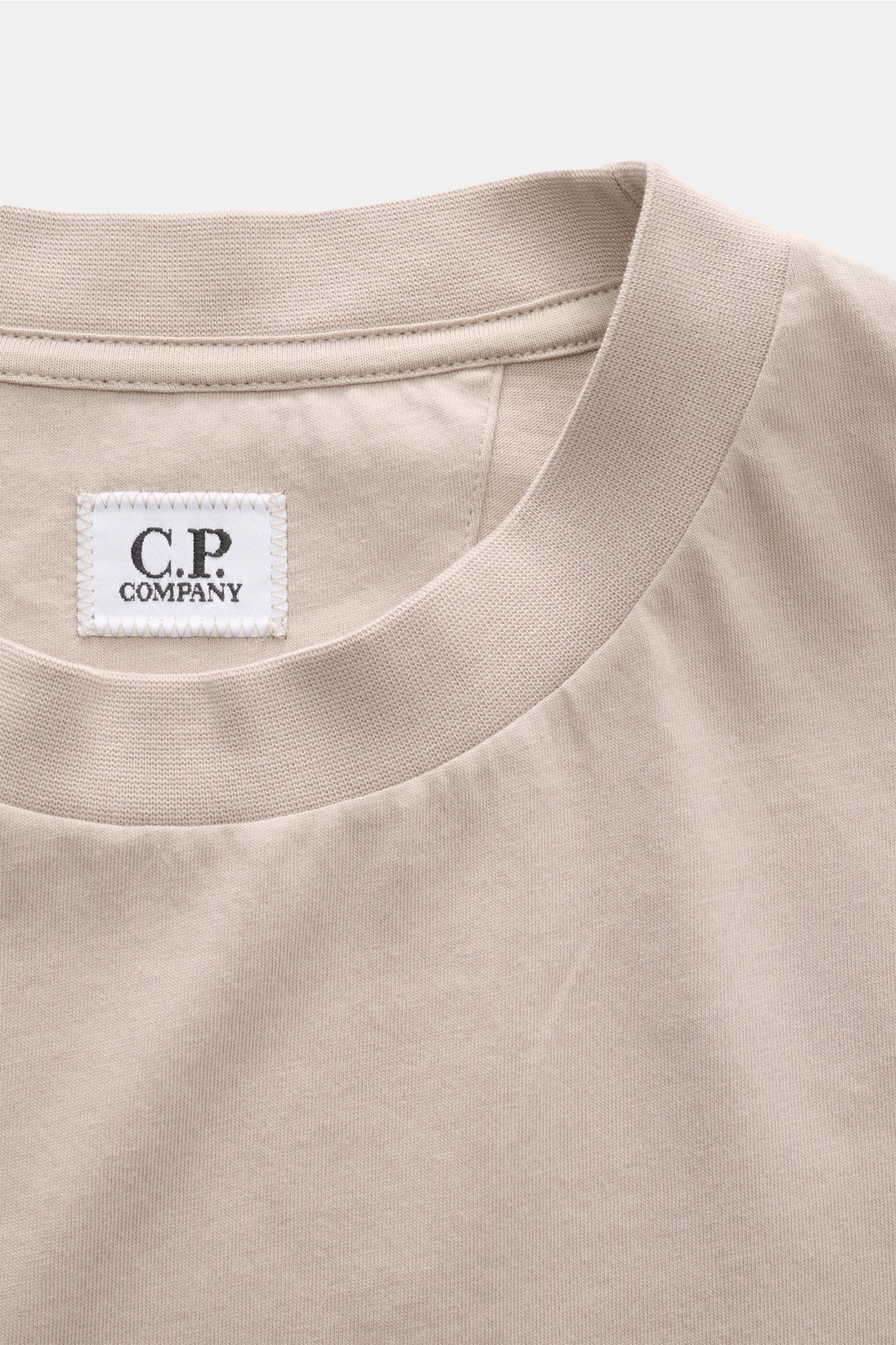 Nahaufnahme des Rundhalsausschnitts und des C.P. Company T-Shirt beige Labels, aus reiner Baumwolle mit weichem Griff, Slim Fit, Logo-Print auf Brust und großem Backprint.