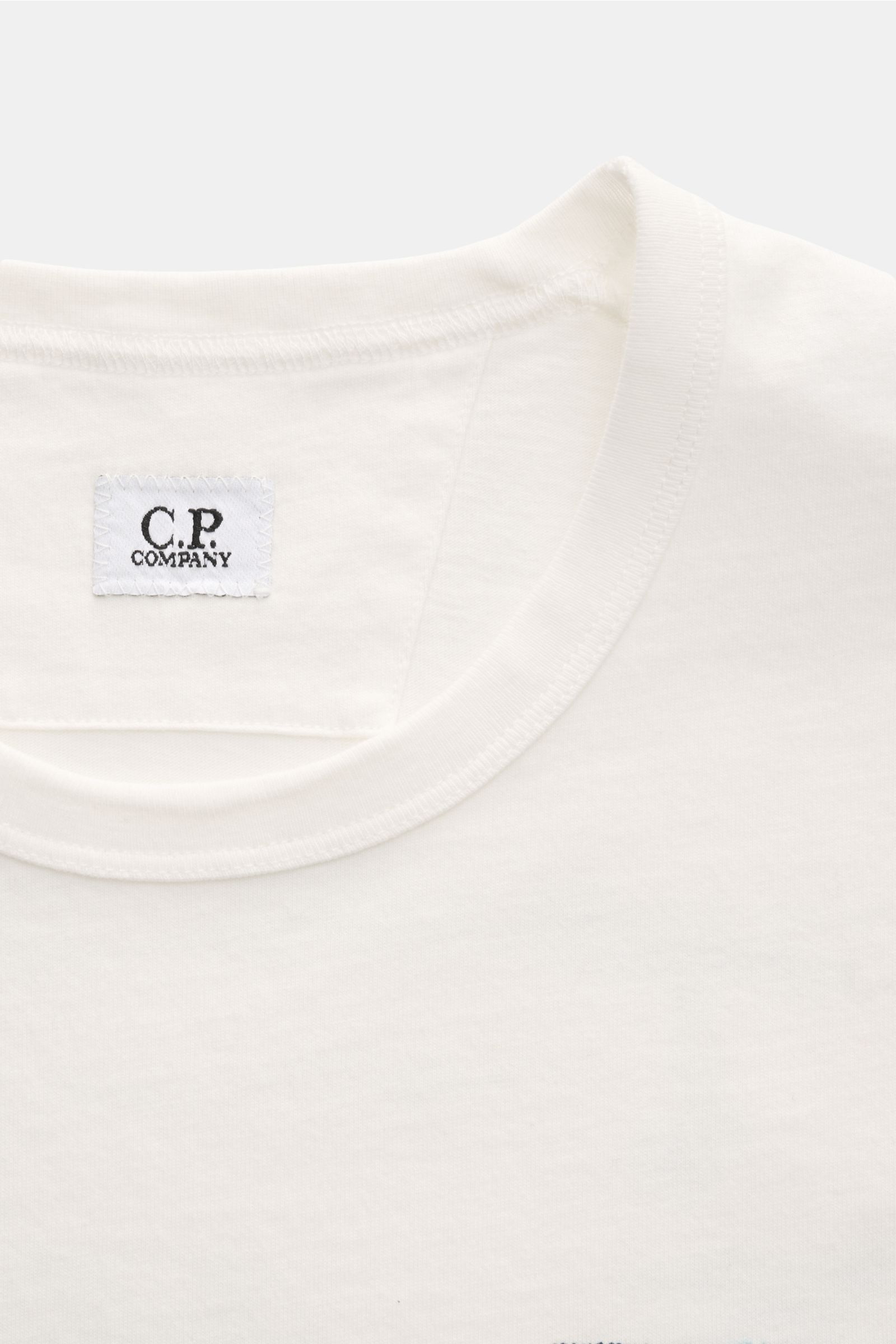 Close-up front view of C.P. Company T-Shirt creme showing round neckline and logo label inside collar, made of pure cotton.

Description: Sommerliche Leichtigkeit: Mit seinem ausdrucksstarken Backprint und reiner Baumwollqualität versprüht das T-Shirt 