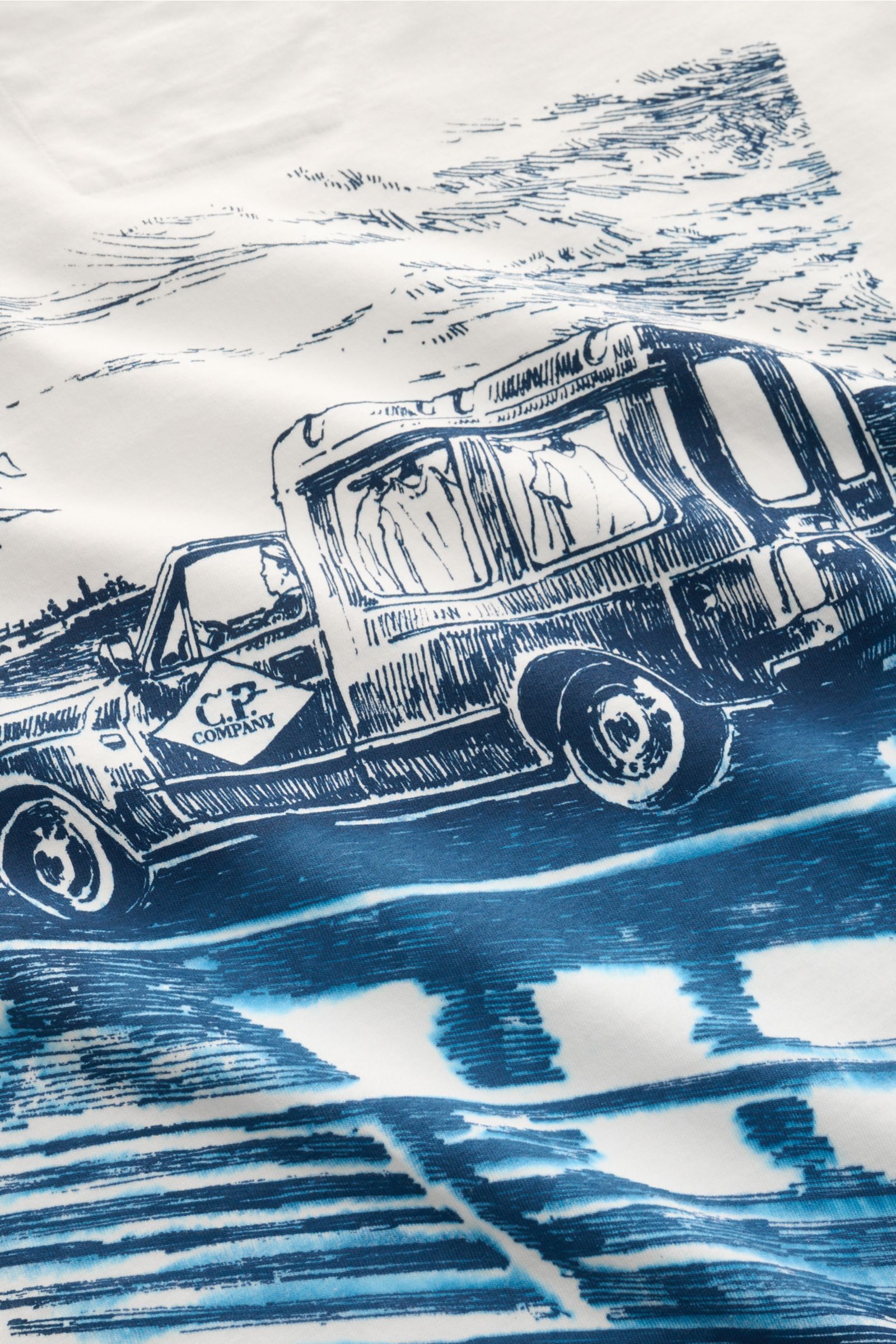 Close-up of the large blue backprint on the creme C.P. Company T-Shirt showing a vintage truck on water, photographed from above.

Sommerliche Leichtigkeit: Mit seinem ausdrucksstarken Backprint und reiner Baumwollqualität versprüht das T-Shirt von C.P