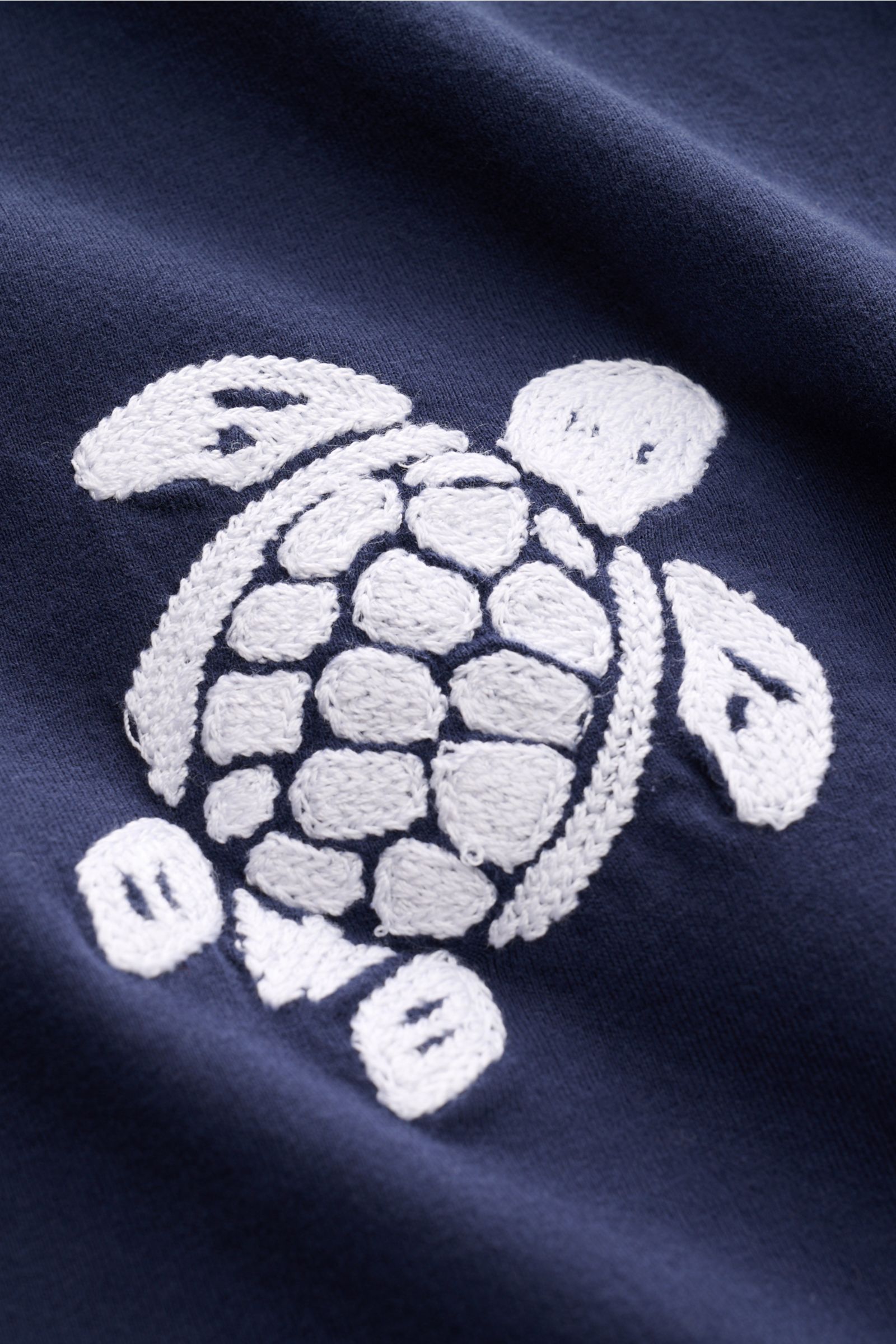 Nahaufnahme des Vilebrequin Rundhals-T-Shirts 'Partisol' navy mit aufwändigem weißen Schildkröten-Stitching auf softem Baumwoll-Jersey.