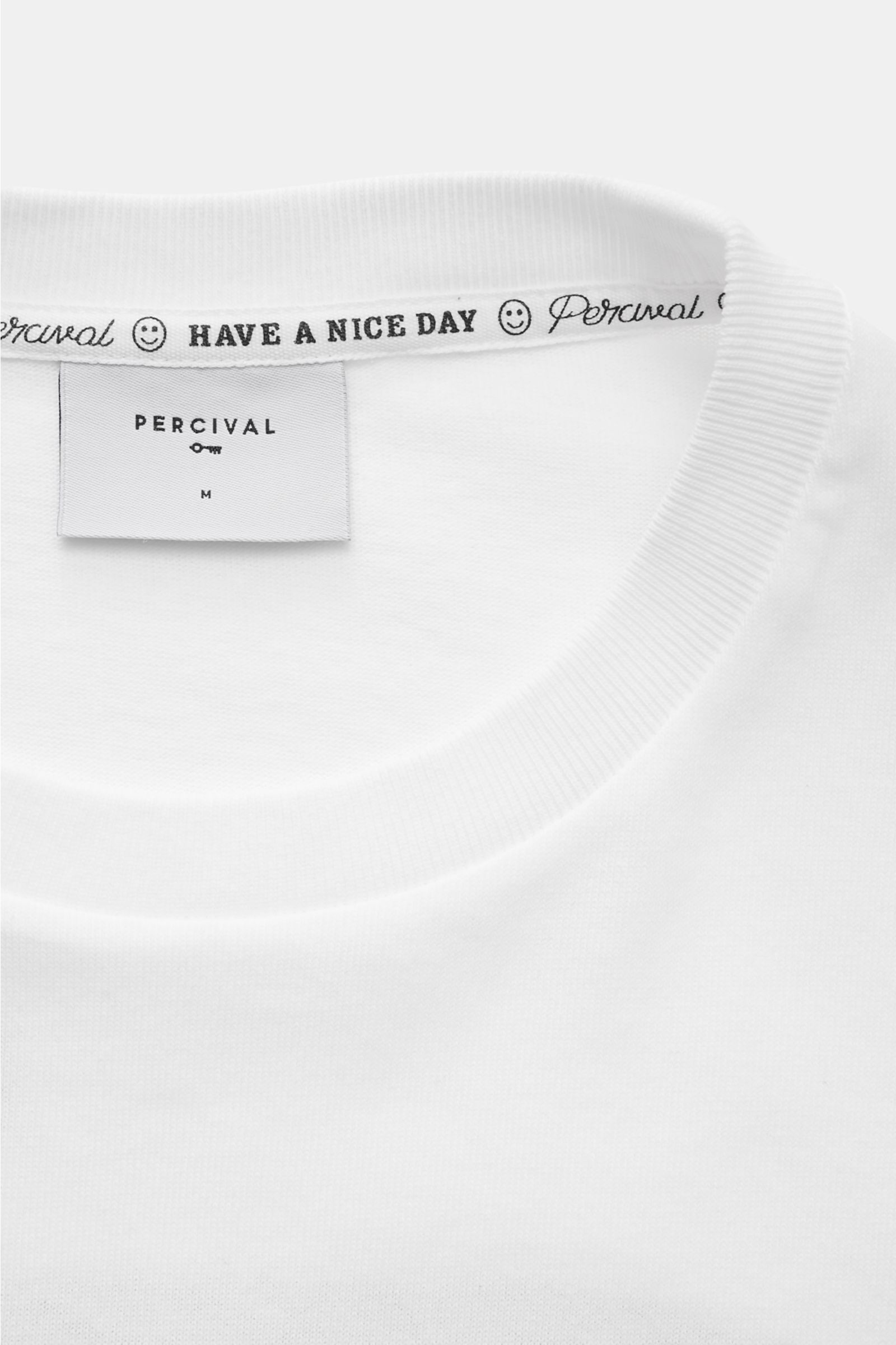 Close-up front view of Percival T-Shirt 'Perci Loaf' weiß showing ribbed round neckline and inner label with 'HAVE A NICE DAY' print. Cool durch den Sommer: Das T-Shirt von PERCIVAL überzeugt mit relaxed Fit und setzt mit seinem markanten Katzen-Print ein
