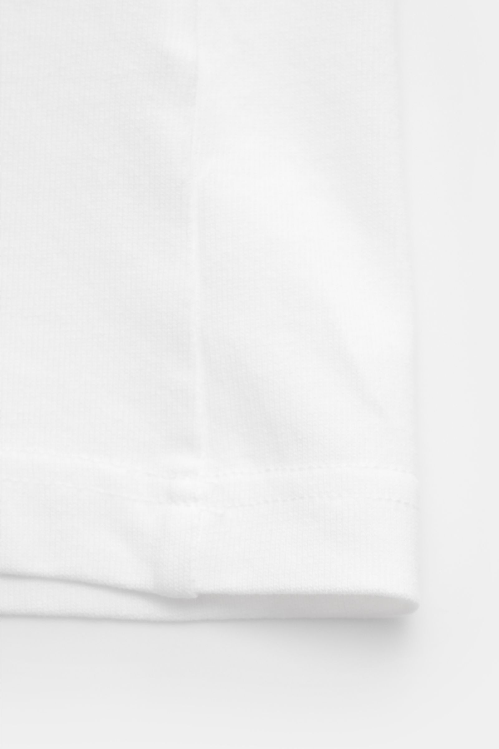 White fabric close-up of the hem and stitching of the Percival T-Shirt 'Perci Loaf' weiß, photographed from a top-down perspective. Cool durch den Sommer: Das T-Shirt von PERCIVAL überzeugt mit relaxed Fit und setzt mit seinem markanten Katzen-Print ei