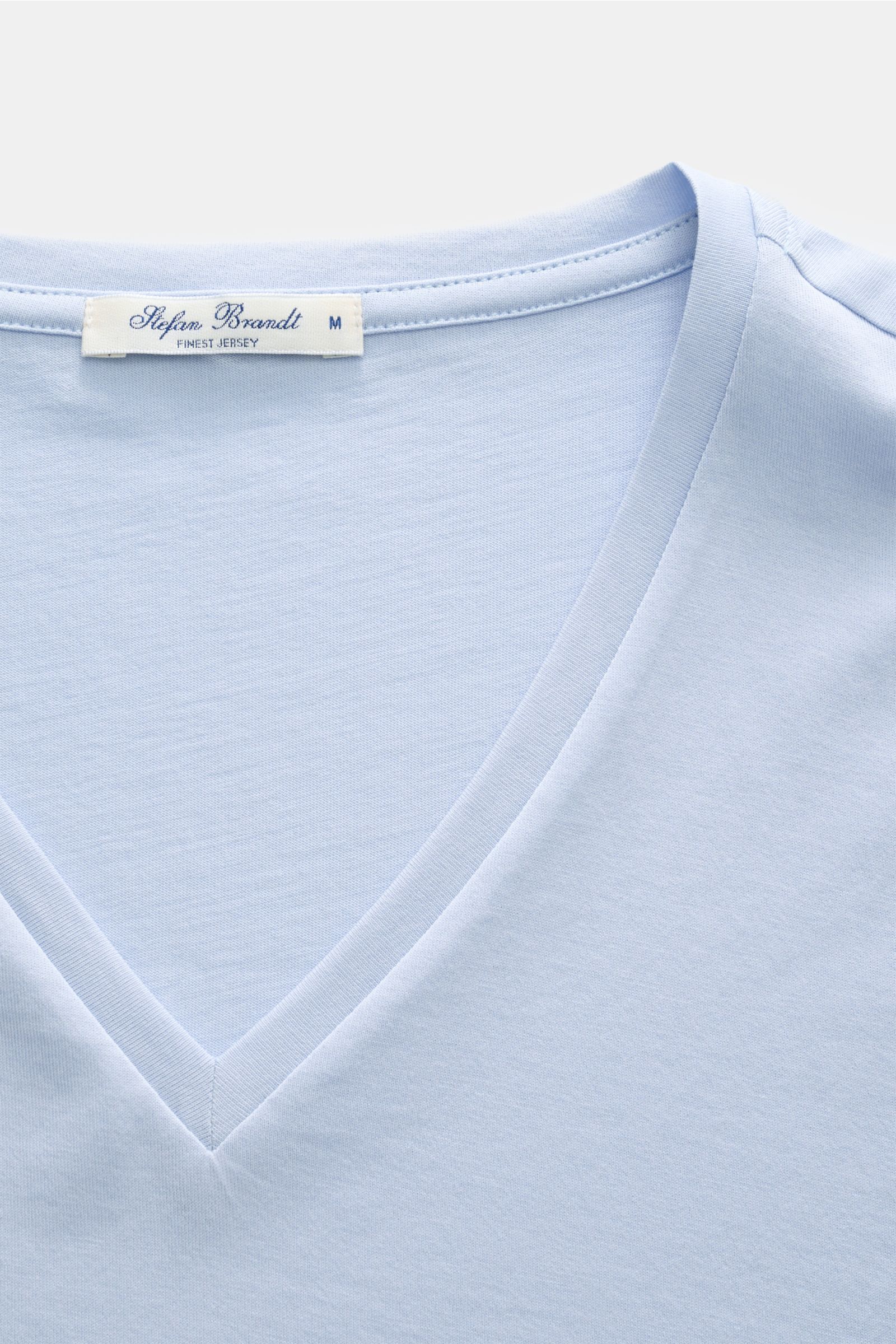 Close-up, top-down view of the Stefan Brandt V-Neck T-Shirt 'Artur' hellblau in light blue, showcasing the V-neck and label. Luxuriöses Essential: Das V-Neck T-Shirt 'Artur' von STEFAN BRANDT aus edler 'Urpima Sea Island' Baumwolle besticht durch außer