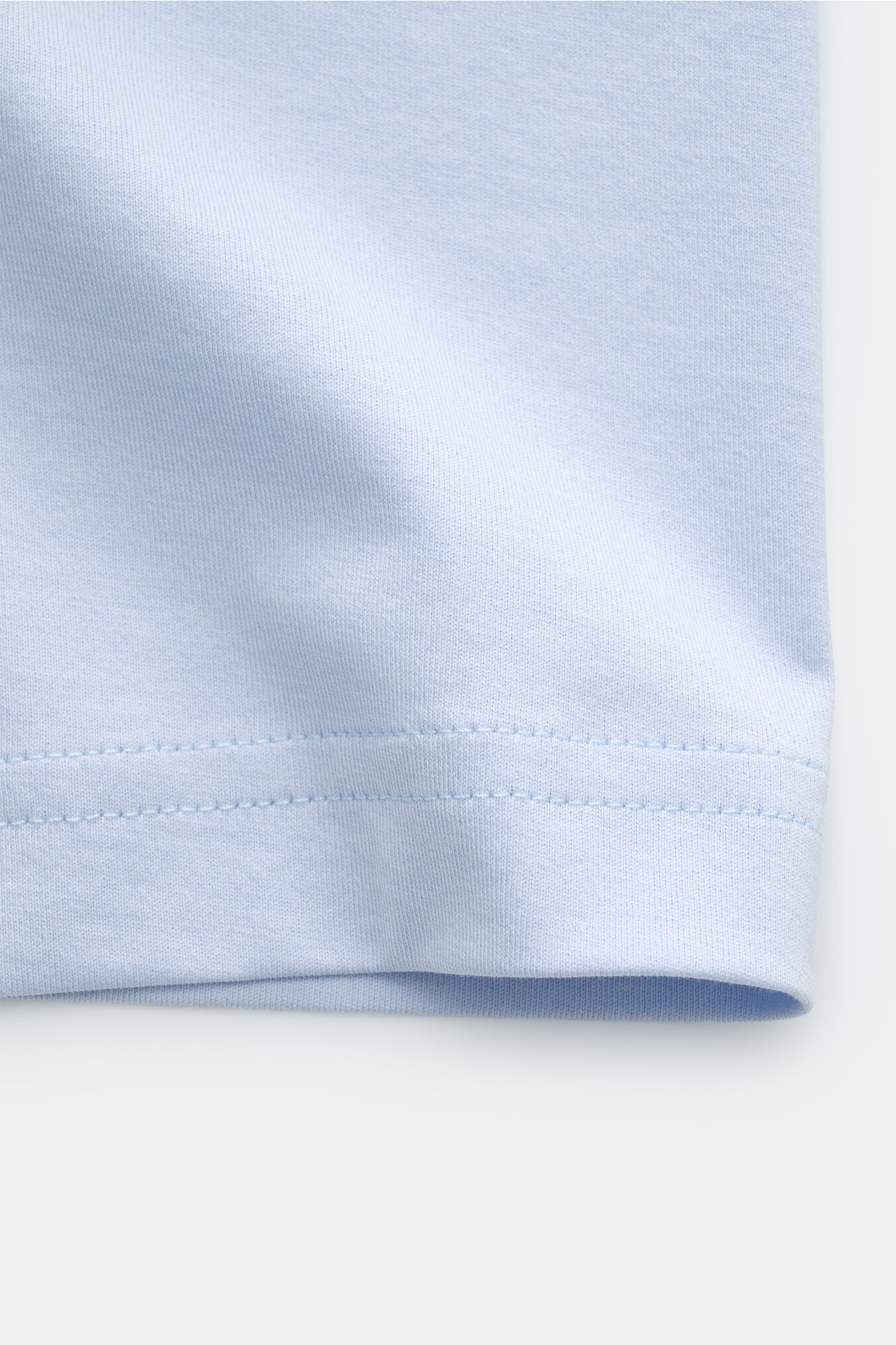 Stefan Brandt V-Neck T-Shirt 'Artur' hellblau close-up of hem stitching, showing soft, light blue fabric from a front angle.  
Luxuriöses Essential: Das V-Neck T-Shirt 'Artur' von STEFAN BRANDT aus edler 'Urpima Sea Island' Baumwolle besticht durch auß